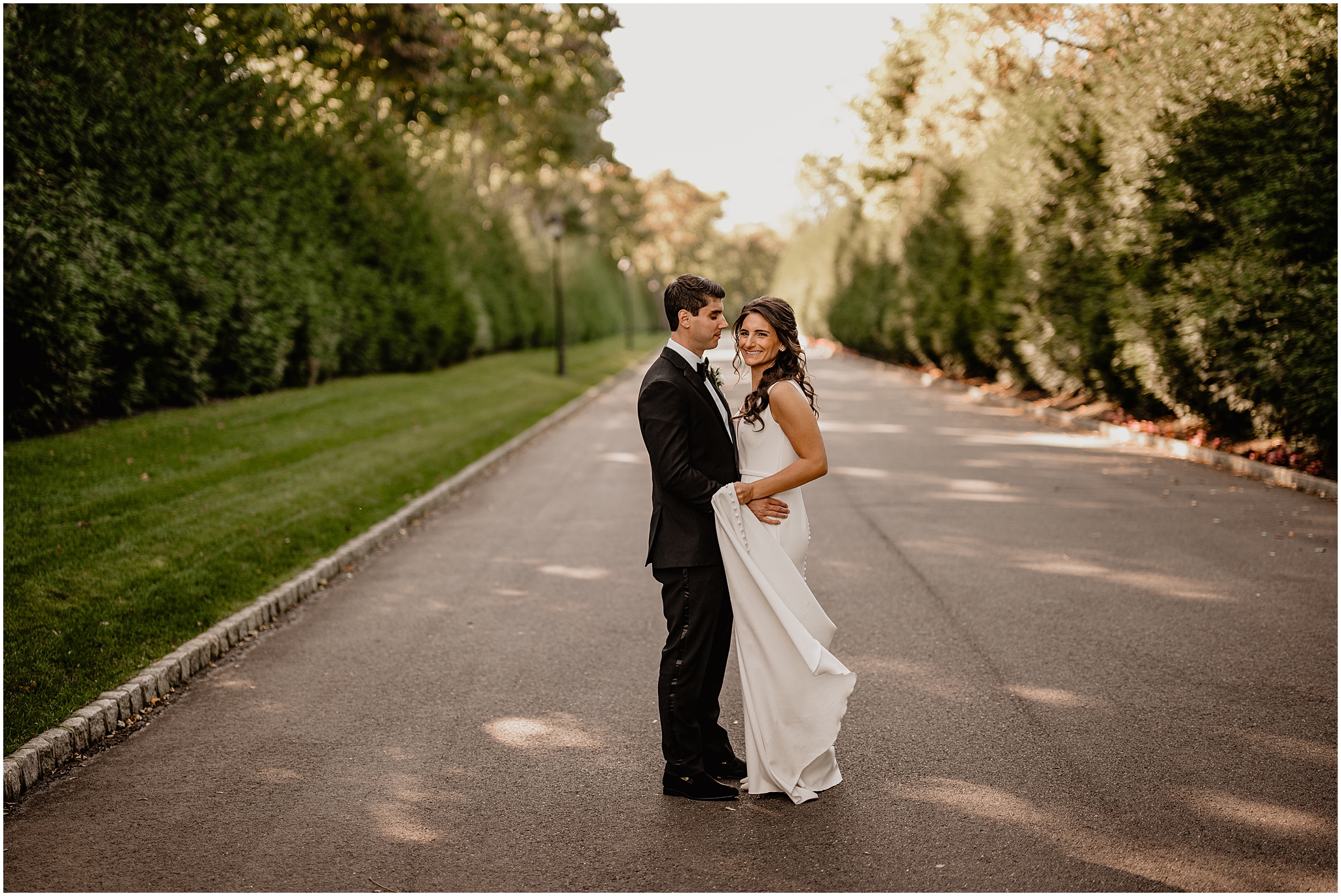 bride and groom hug on driveway of New Jersey wedding venue smiling together 