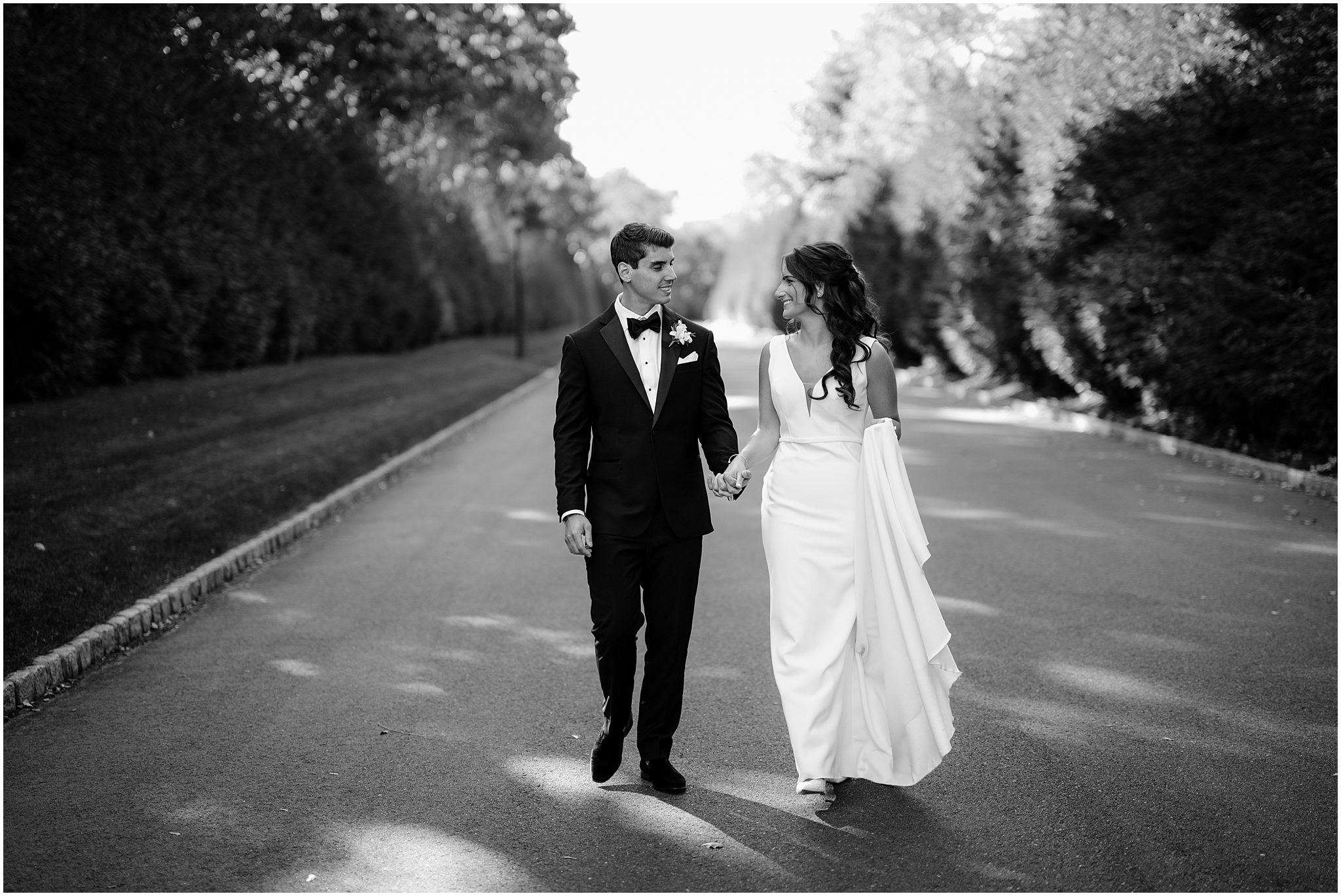 bride and groom hold hands walking down driveway of NJ wedding venue