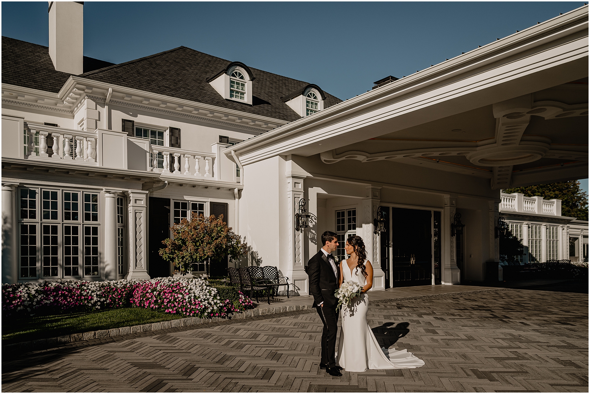 bride and groom stand in front of awning outside the front of The Shadowbrook at Shrewsbury