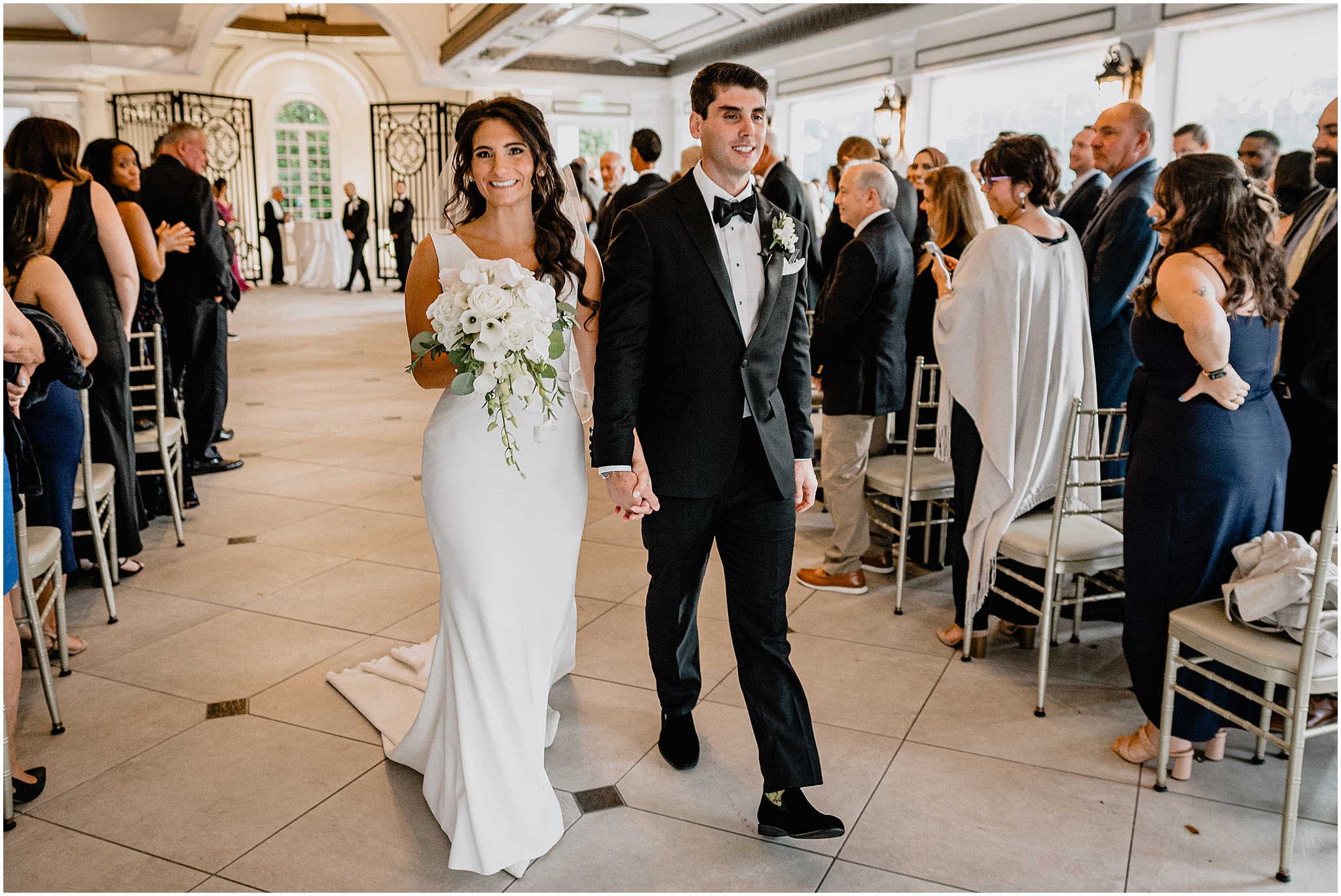 newlyweds hold ands walking up aisle in New Jersey wedding venue 