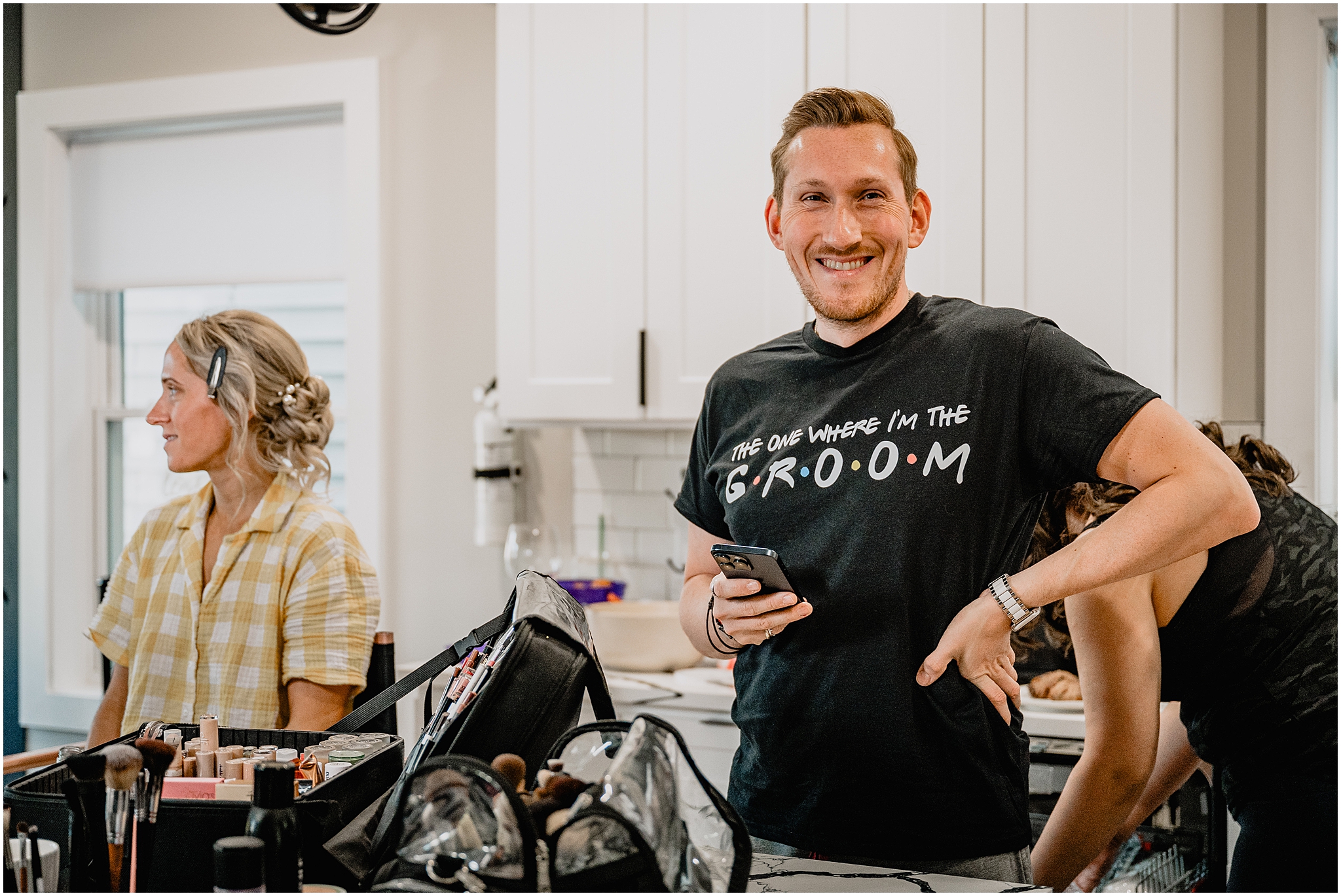 groom smiles standing in FRIENDS themed shirt during wedding day prep