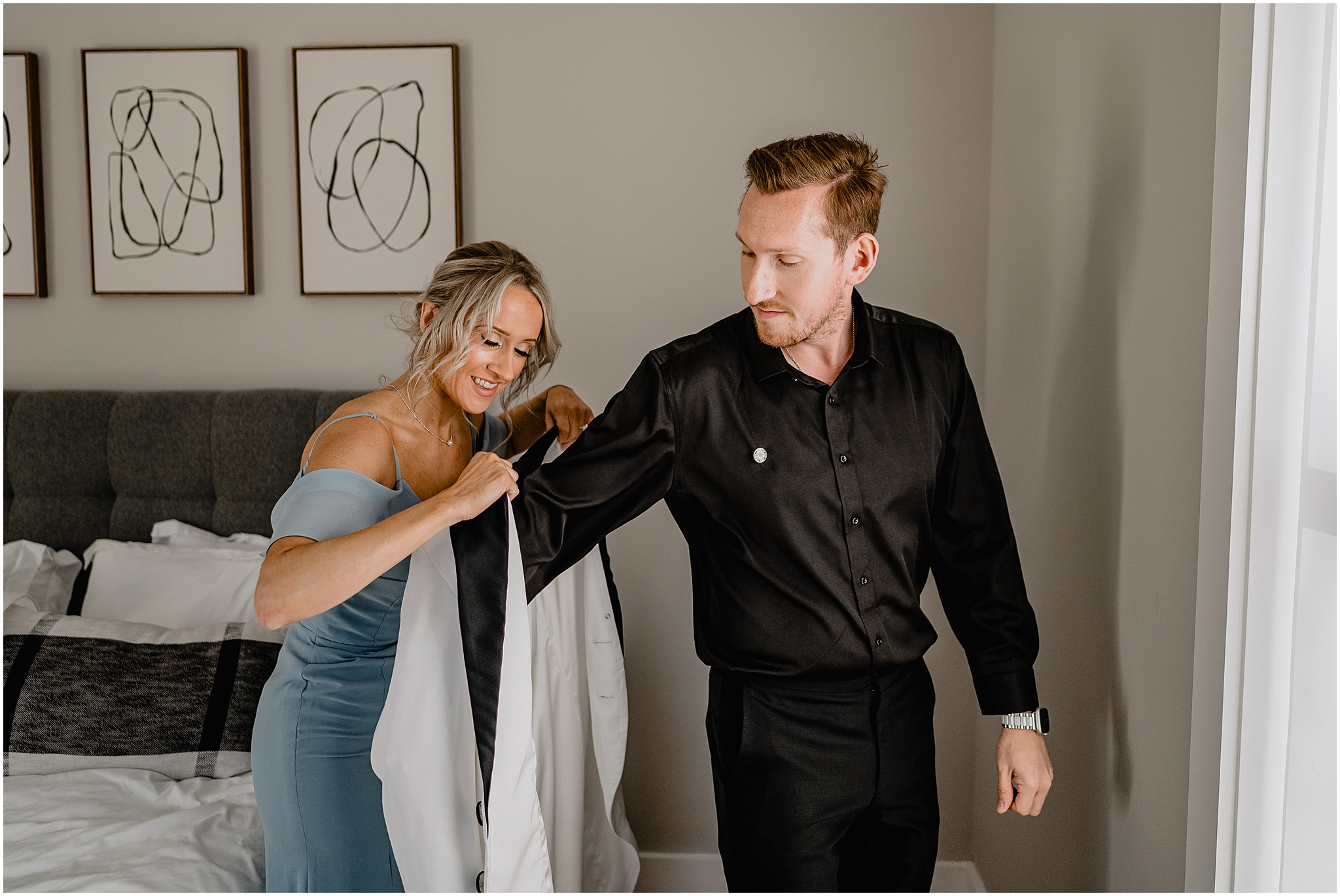 woman helps groom into custom black and white suit jacket for Jersey City wedding