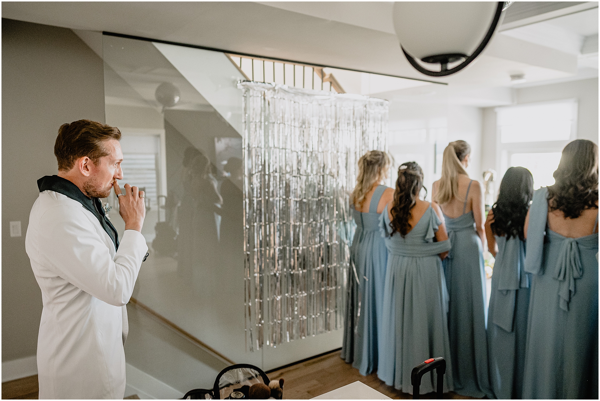 groom in custom white suit jacket approaches bridesmaids for first look