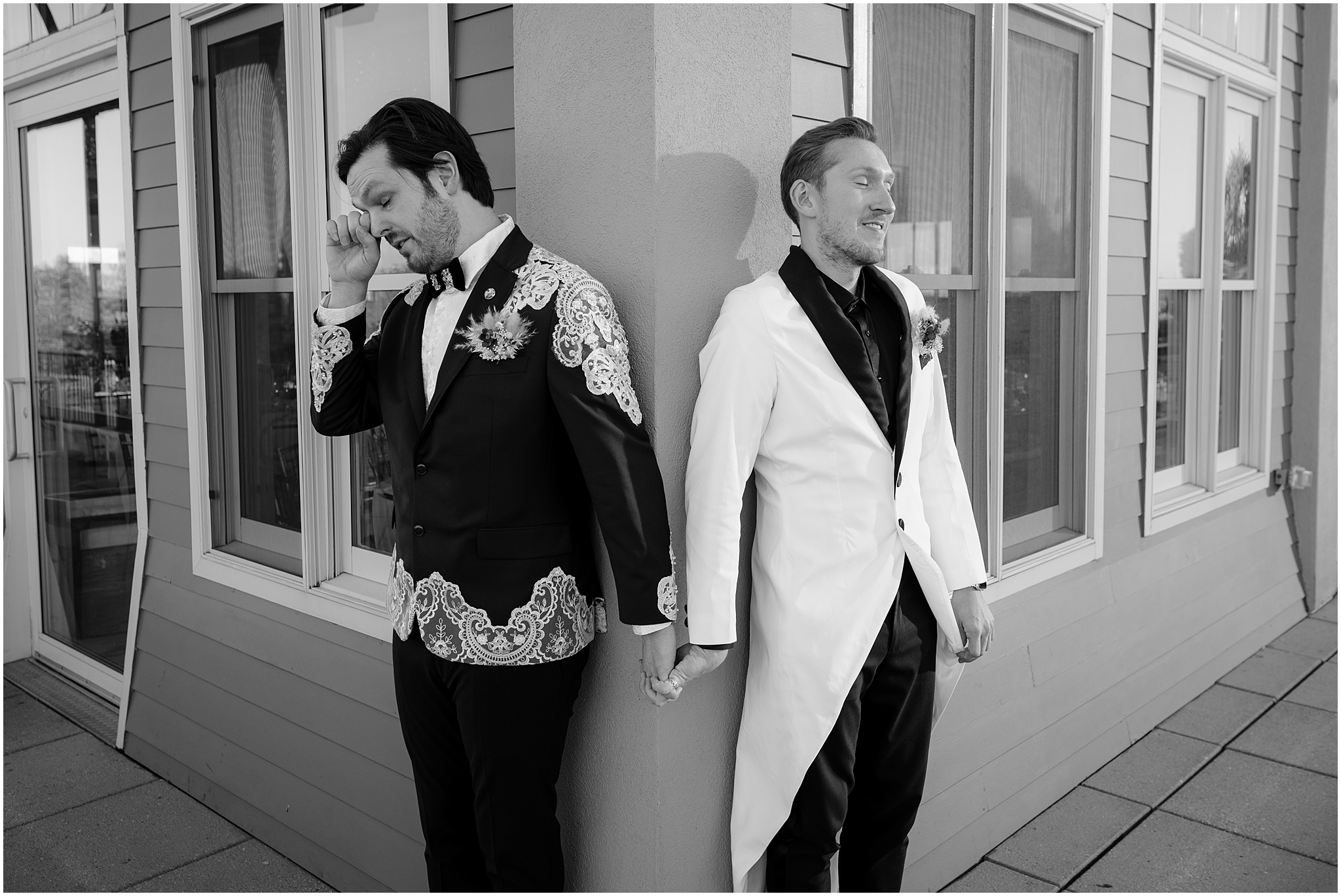 grooms hold hands around corner of the Liberty House in Jersey City for first touch