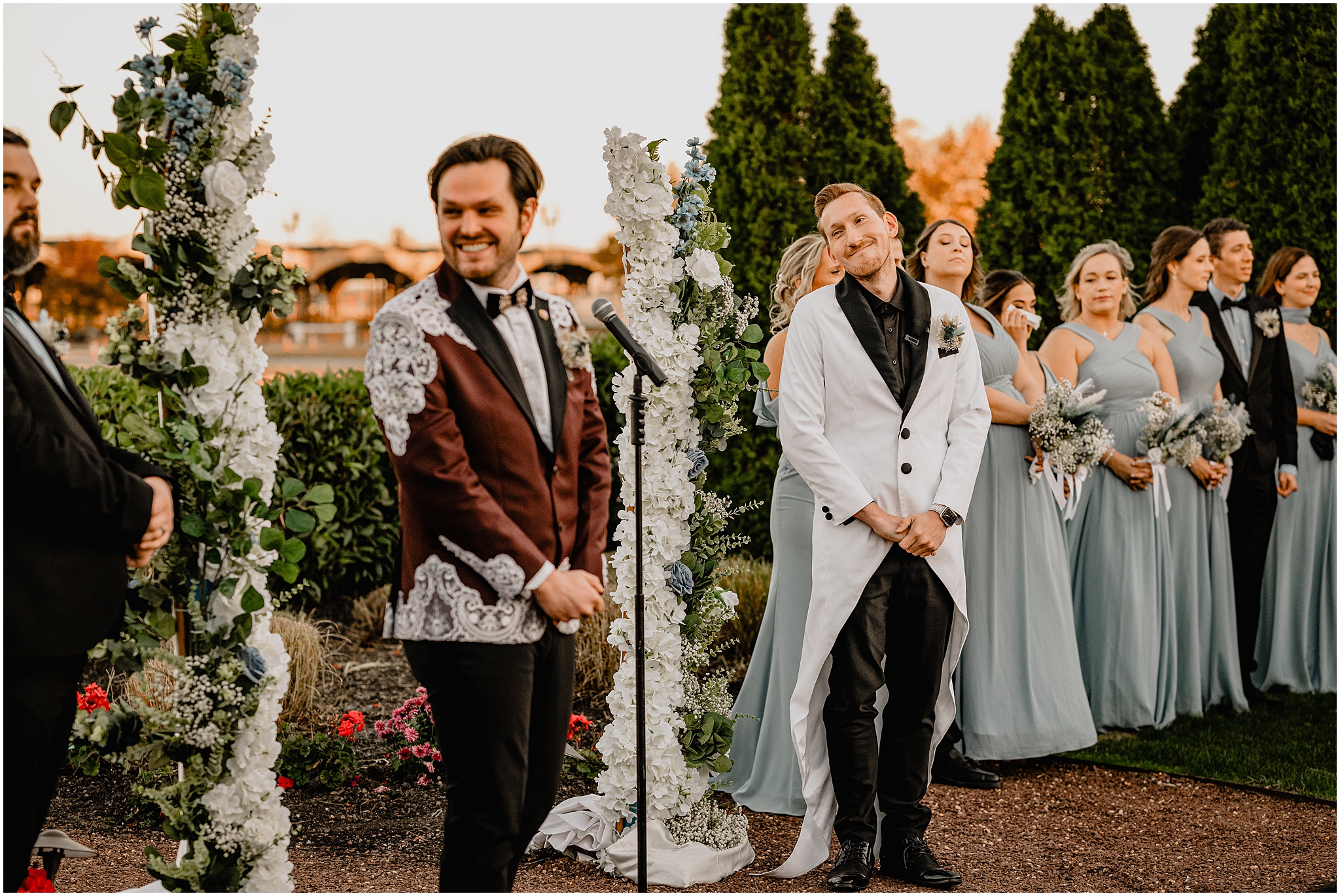 man grins at husband during wedding ceremony on the lawn at the Liberty House in Jersey City