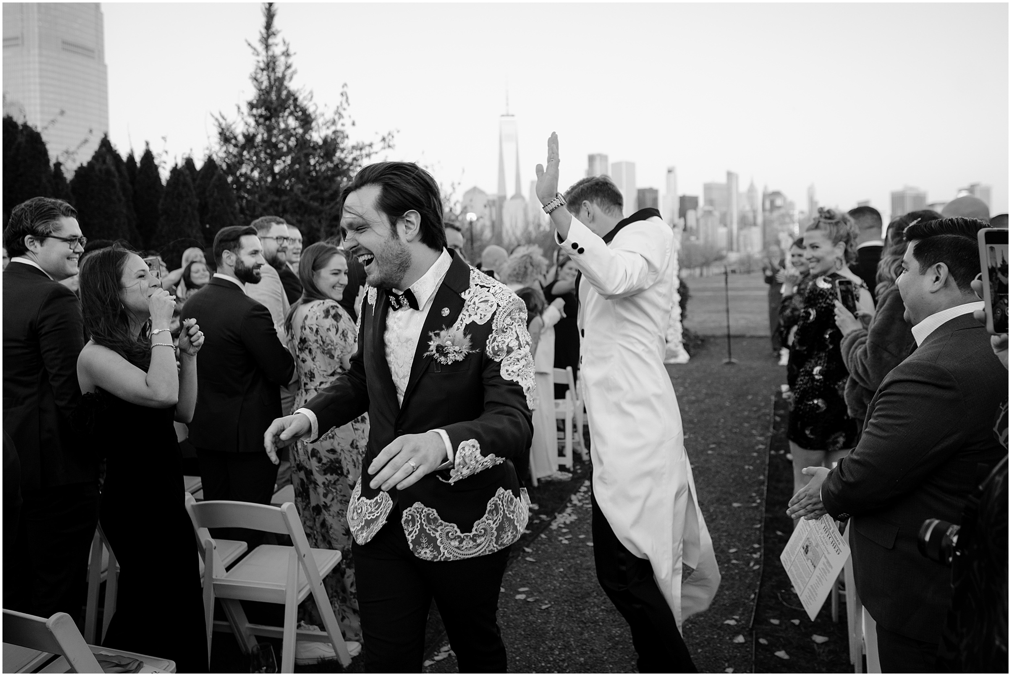 grooms cheer walking up aisle on lawn at the Liberty House in Jersey City