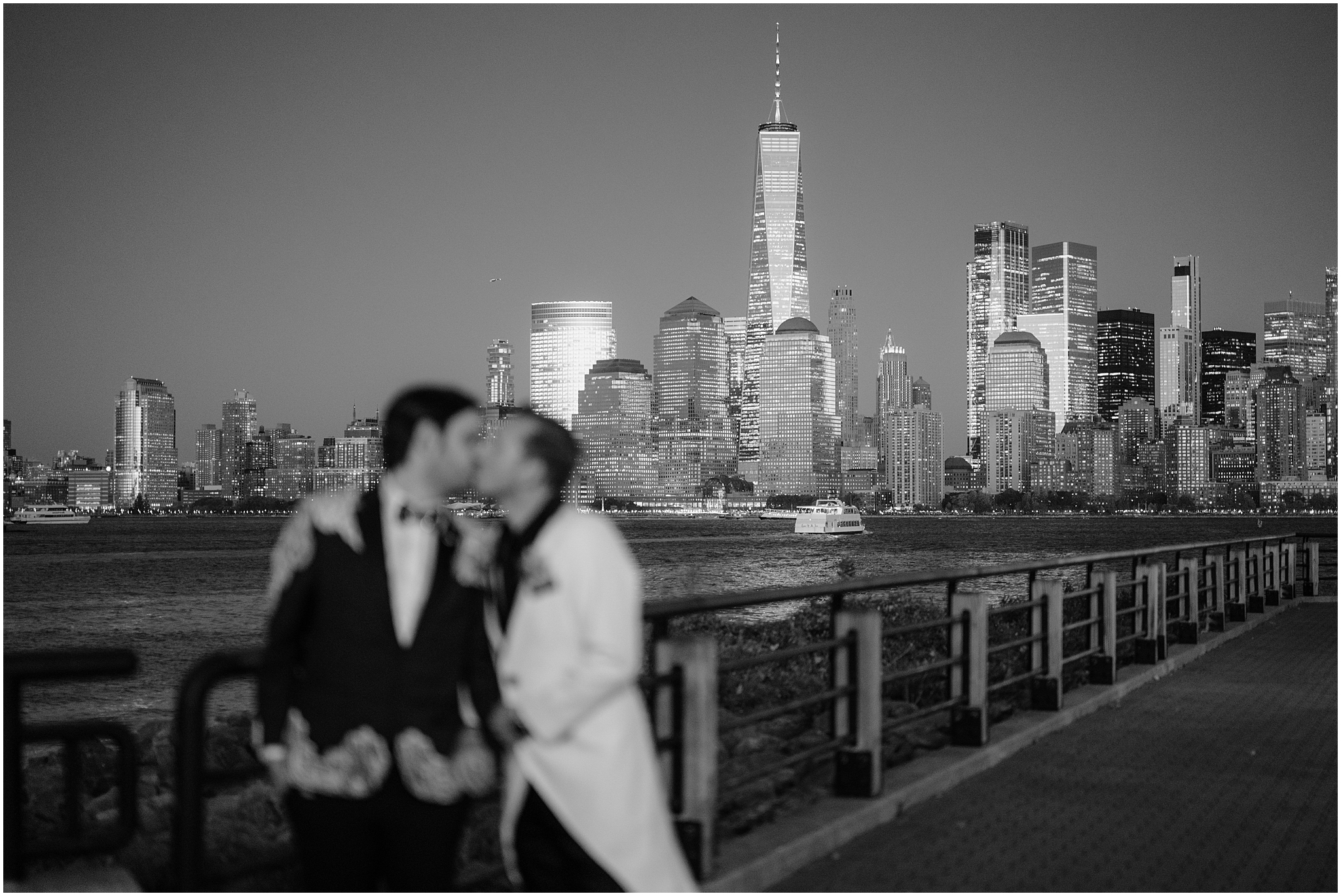 men kiss in foreground of photo with NYC skyline behind them