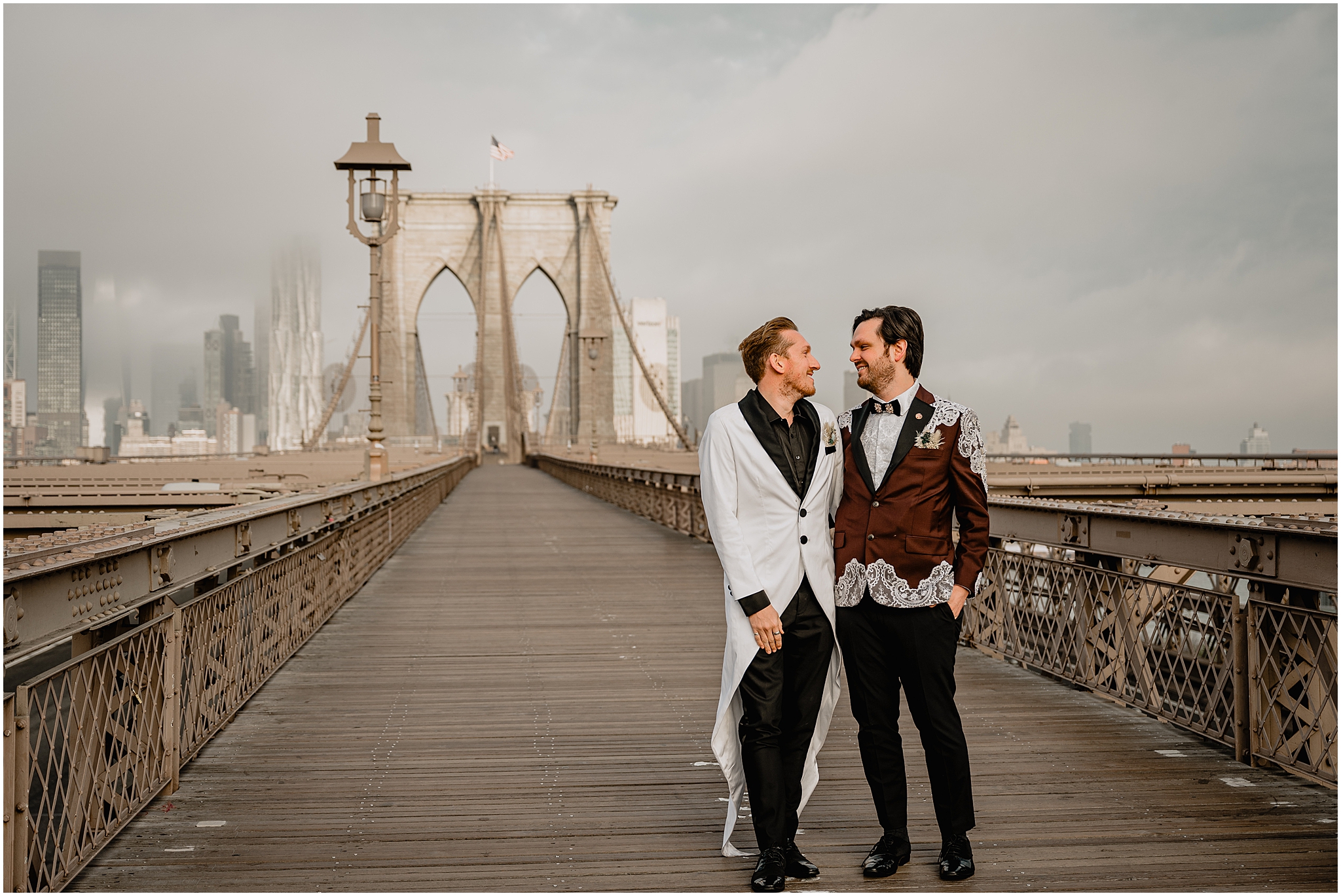 couple hugs standing on Brooklyn Bridge on wedding day 