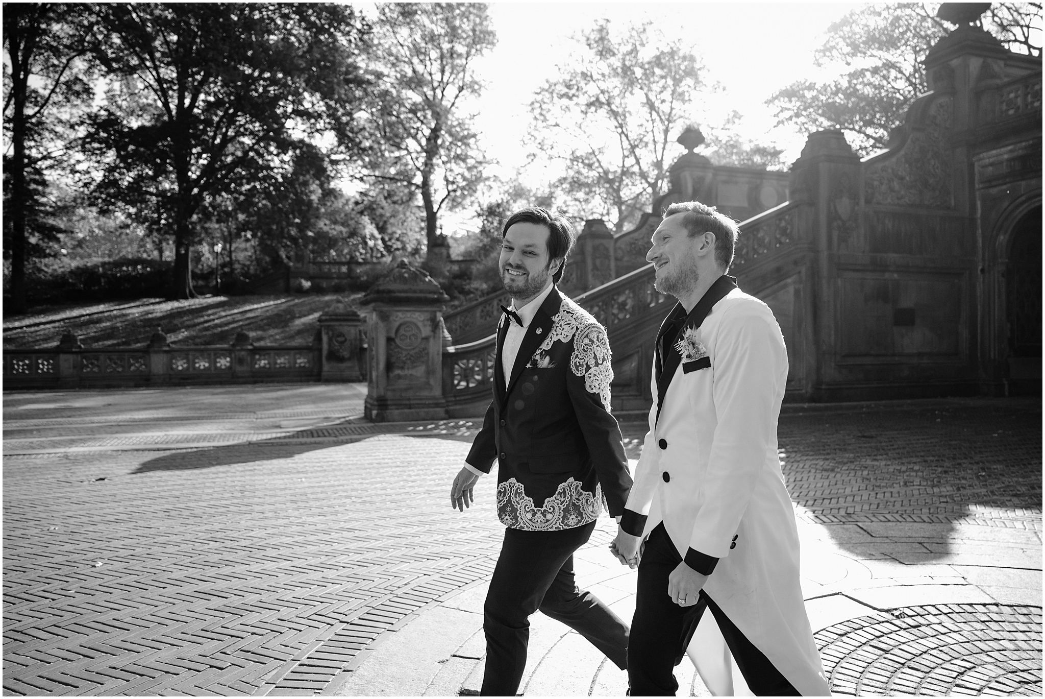 two grooms hold hands walking across the Bethesda Terrace in Central Park 