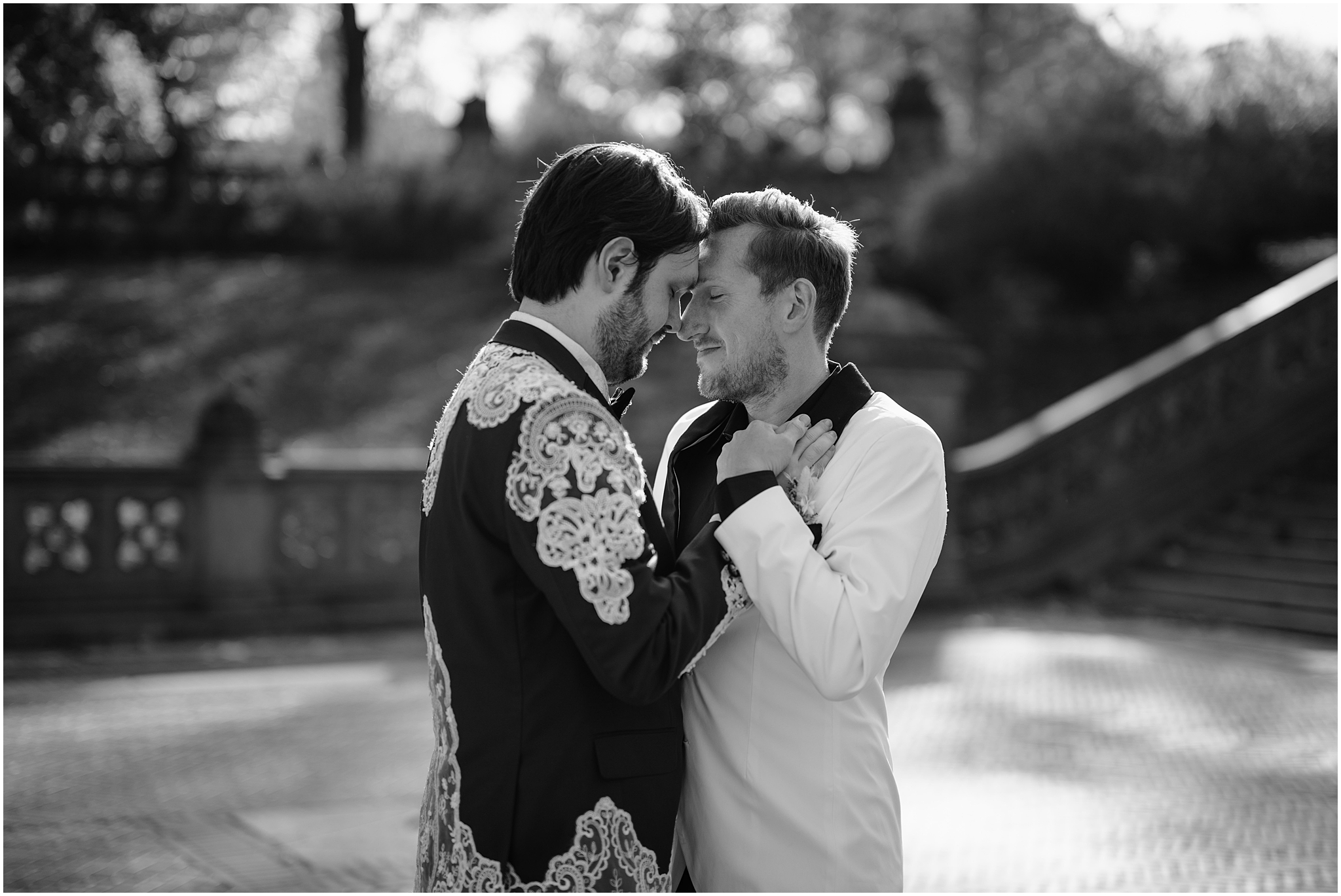 two grooms hug leaning heads together on brick patio on Bethesda Terrace 