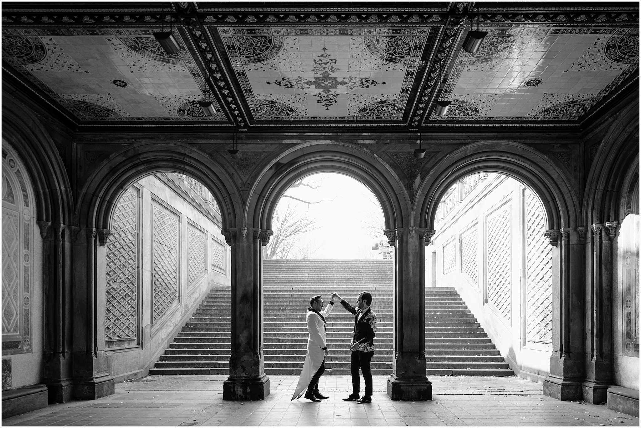 man twirls husband under archway in Central Park terrance 