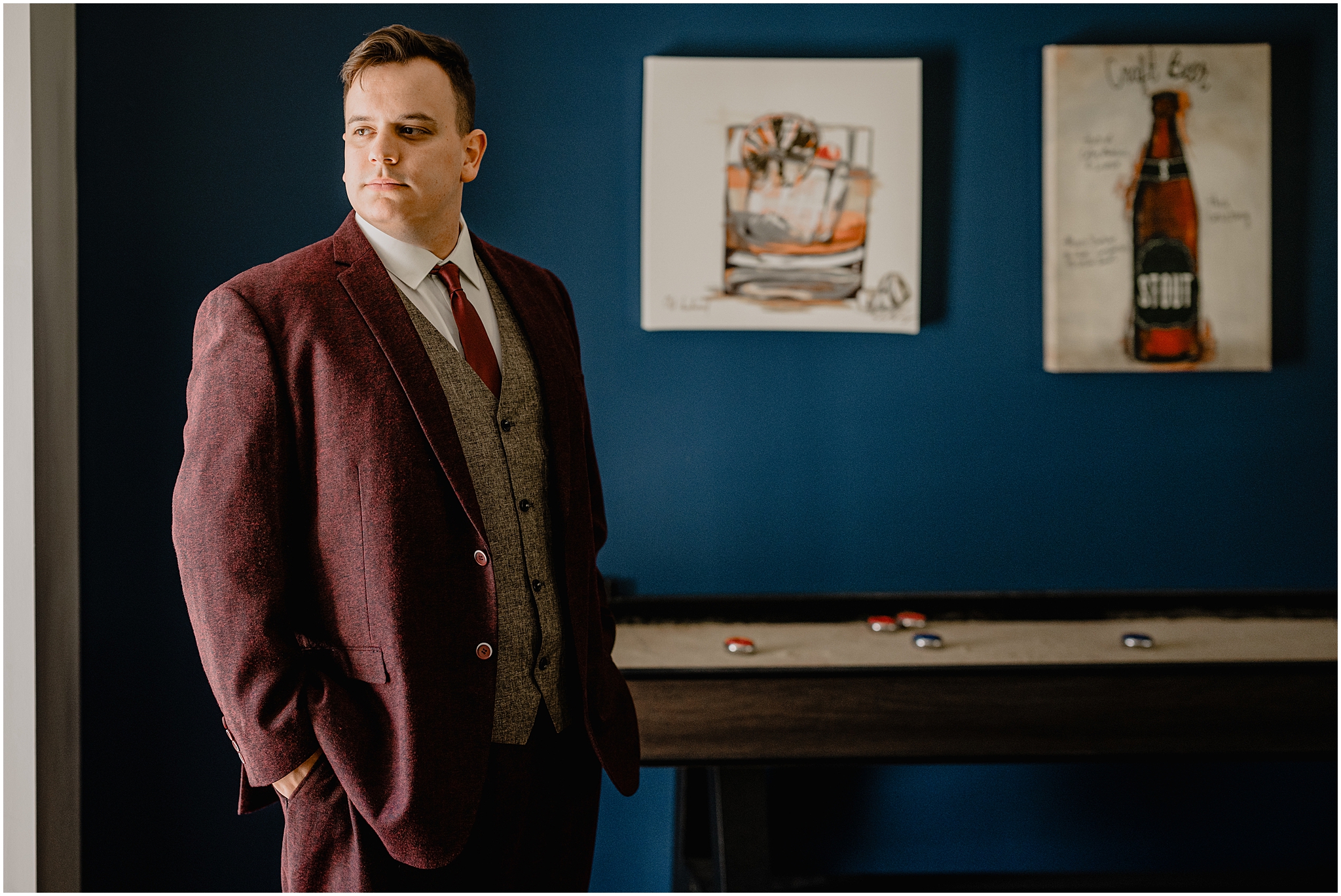 groom stands with hands in pockets in billiards room at the Barn at Perona Farms