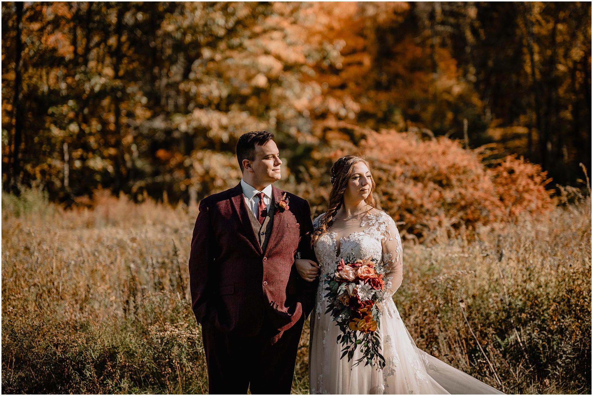 bride and groom smile linking arms with bouquet of red and white flowers 
