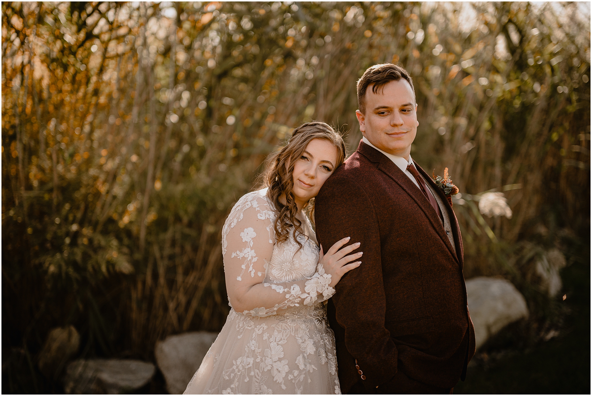 bride Lenas head on groom's shoulder from behind in front of tall grass