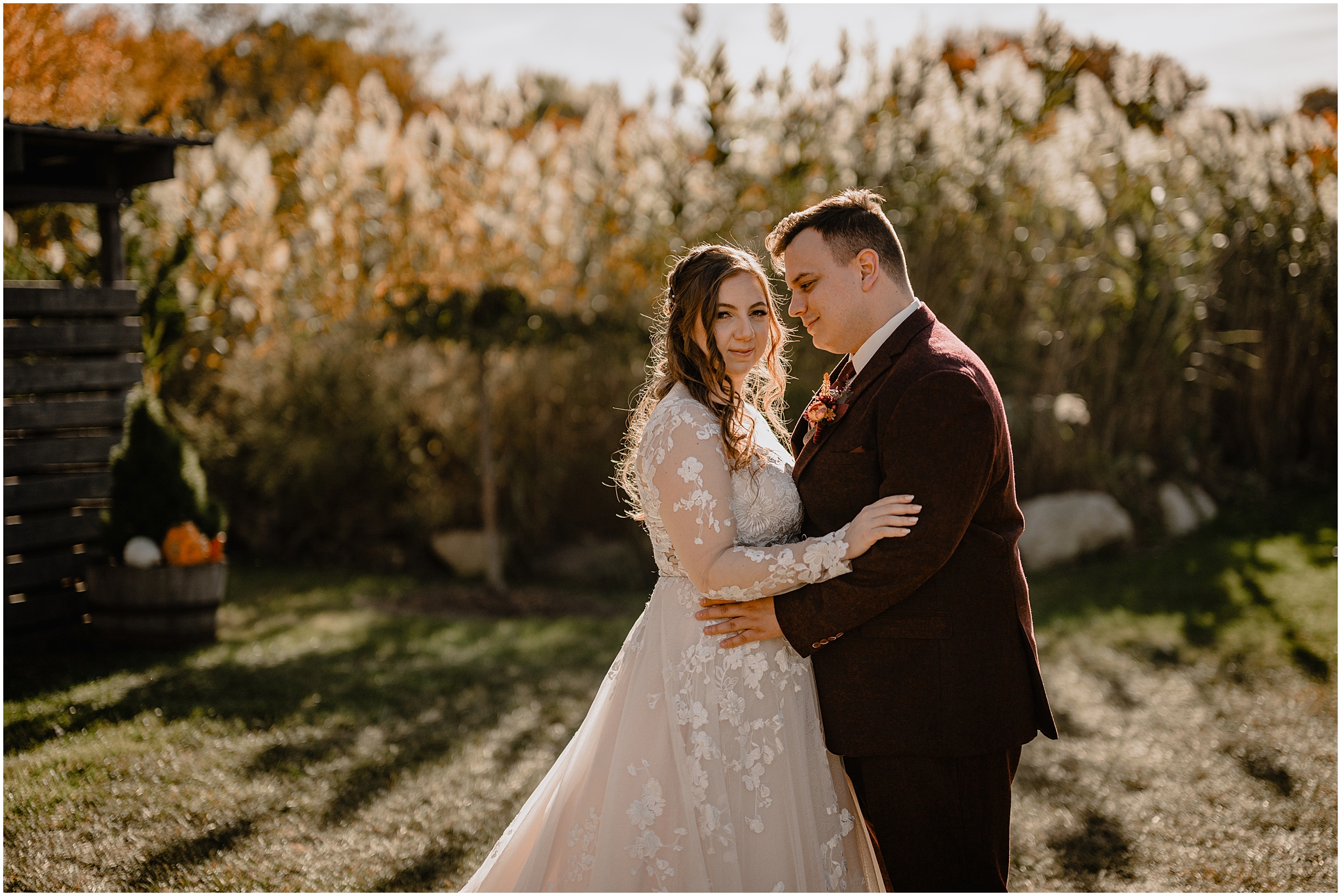 man in burgundy suit hugs woman in wedding gown on the lawn outside the Barn at Perona Farms