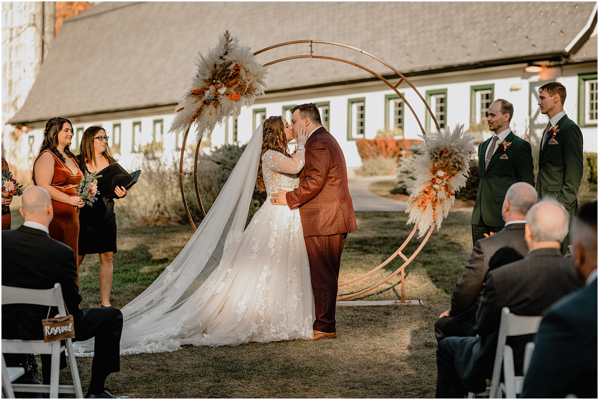 newlyweds kiss in front of circular copper alter at the Barn at Perona Farms