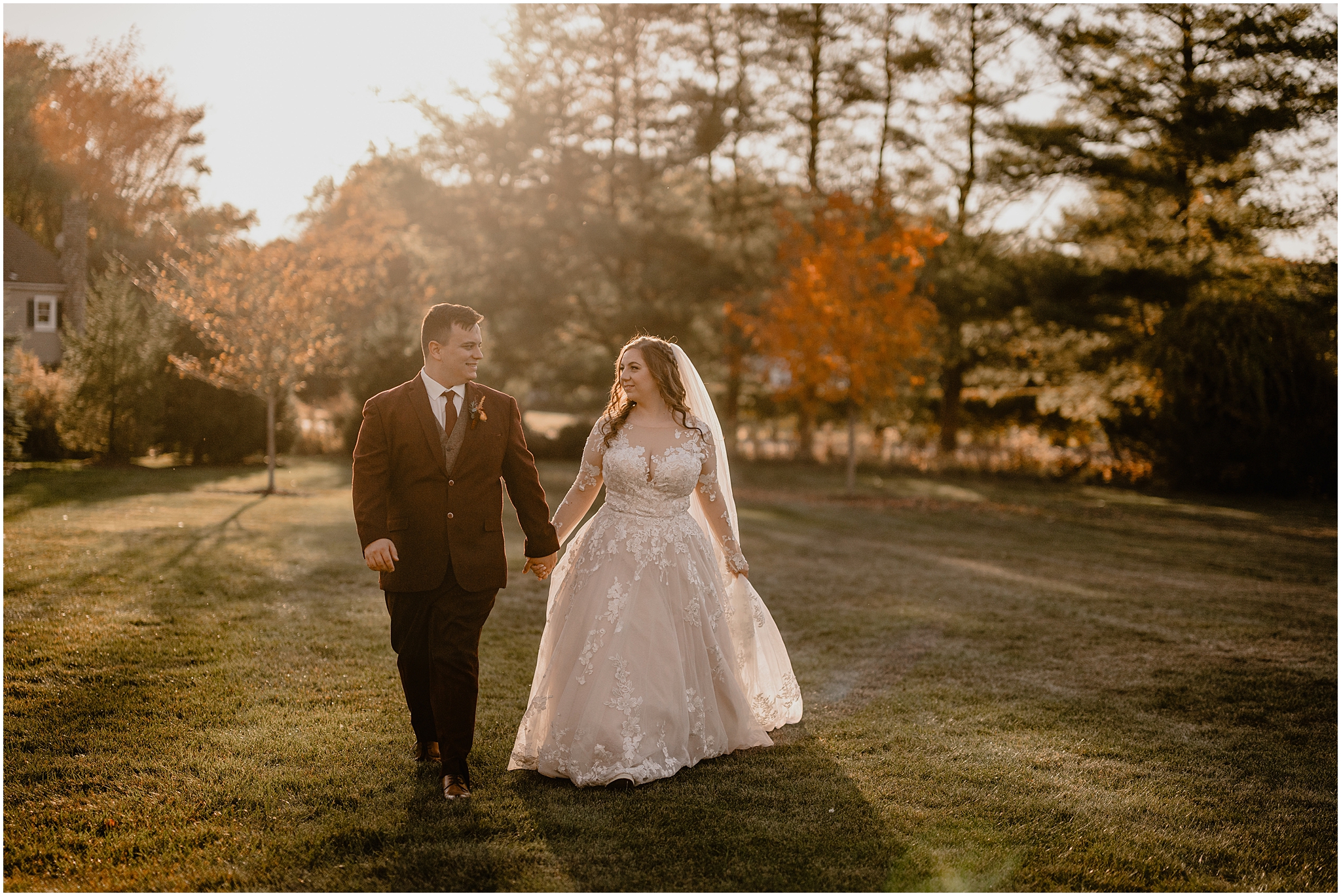 bride and groom hold hands walking together on fall wedding day