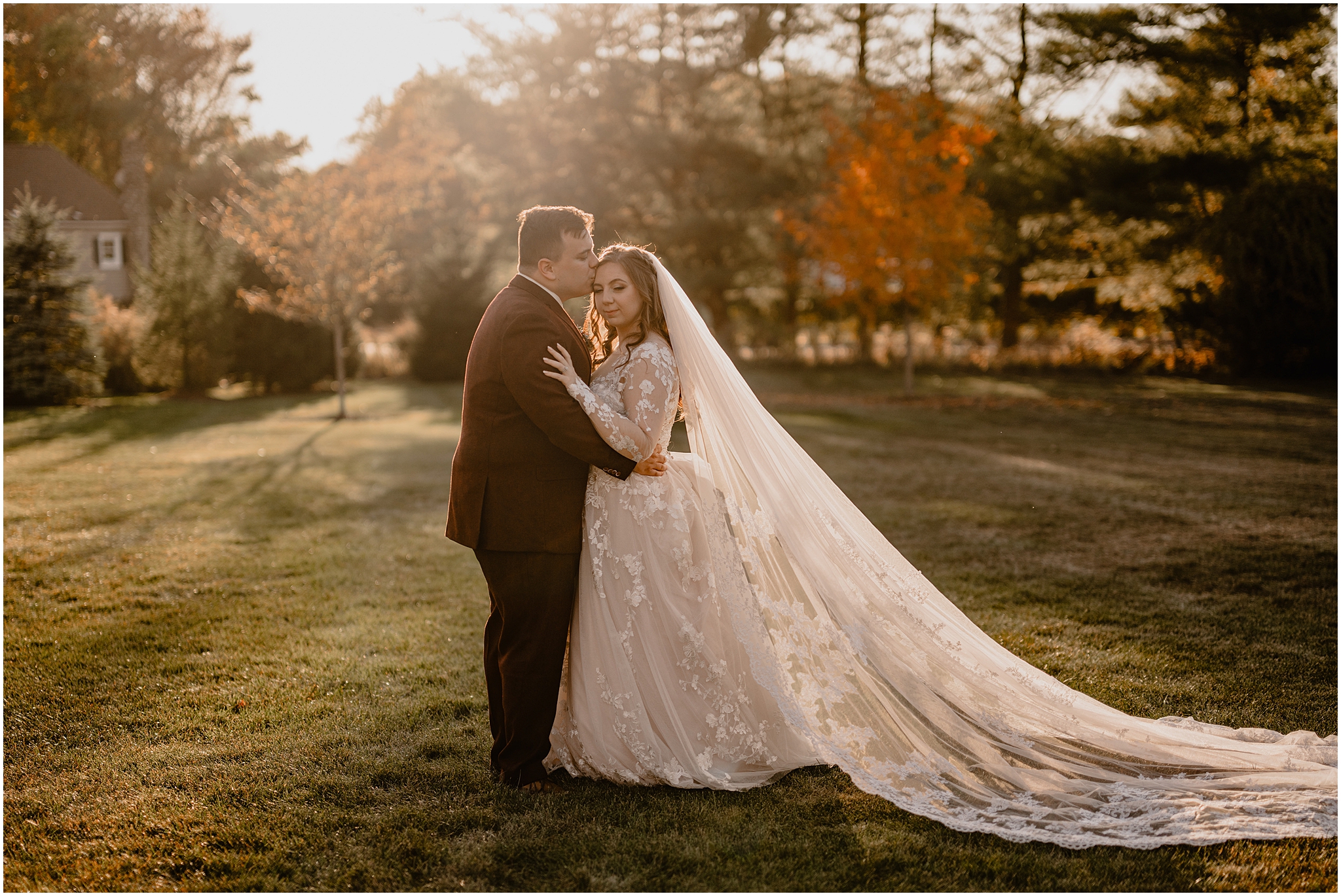 groom kisses bride's forehead standing on lawn at the Barn at Perona Farms