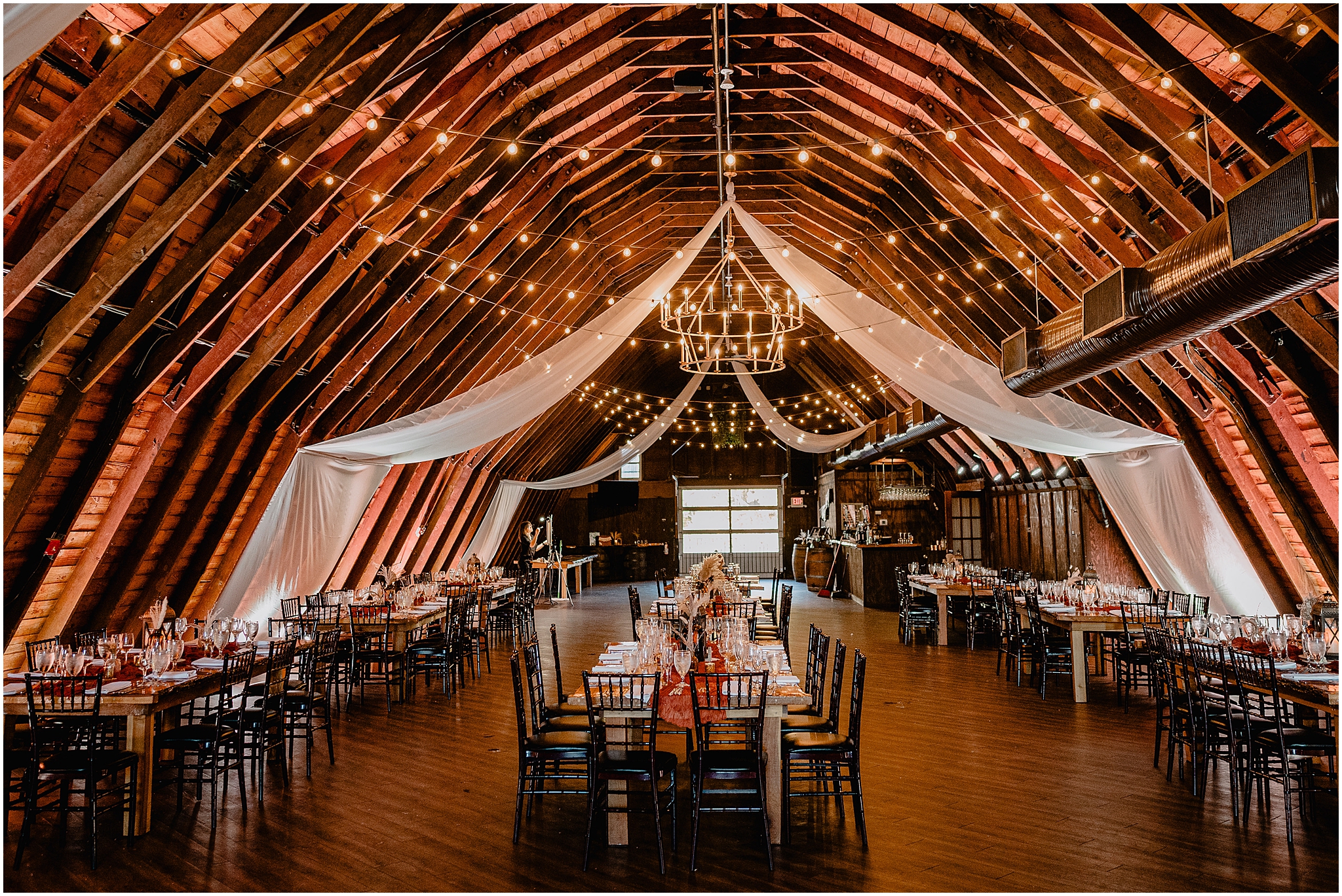 wedding reception in the Barn at Perona Farms with burgundy details, white drapery from the ceiling 