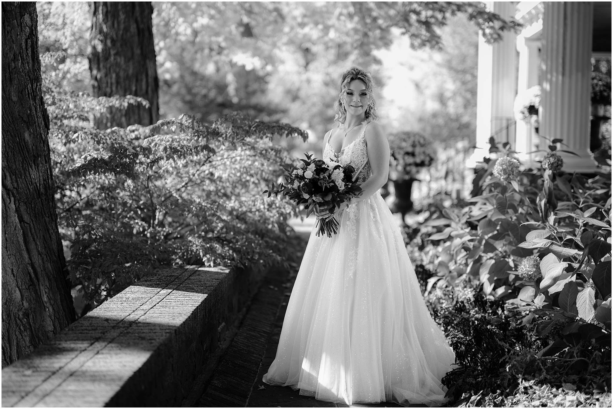 bride holds bouquet standing in gardens of Hudson Valley wedding venue the Feast at Round Hill