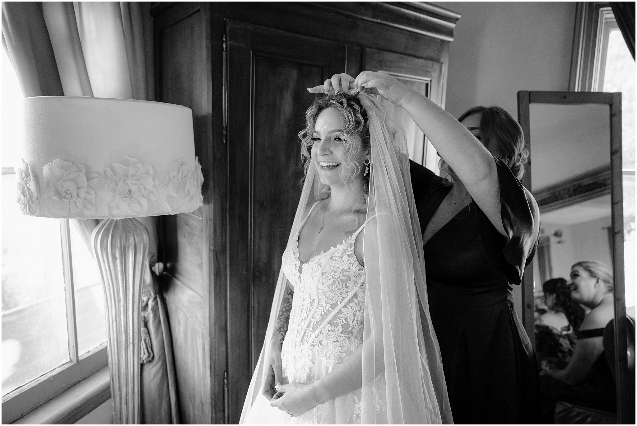 woman places veil for bride while laughing by wooden bureau at the Feast at Round Hill