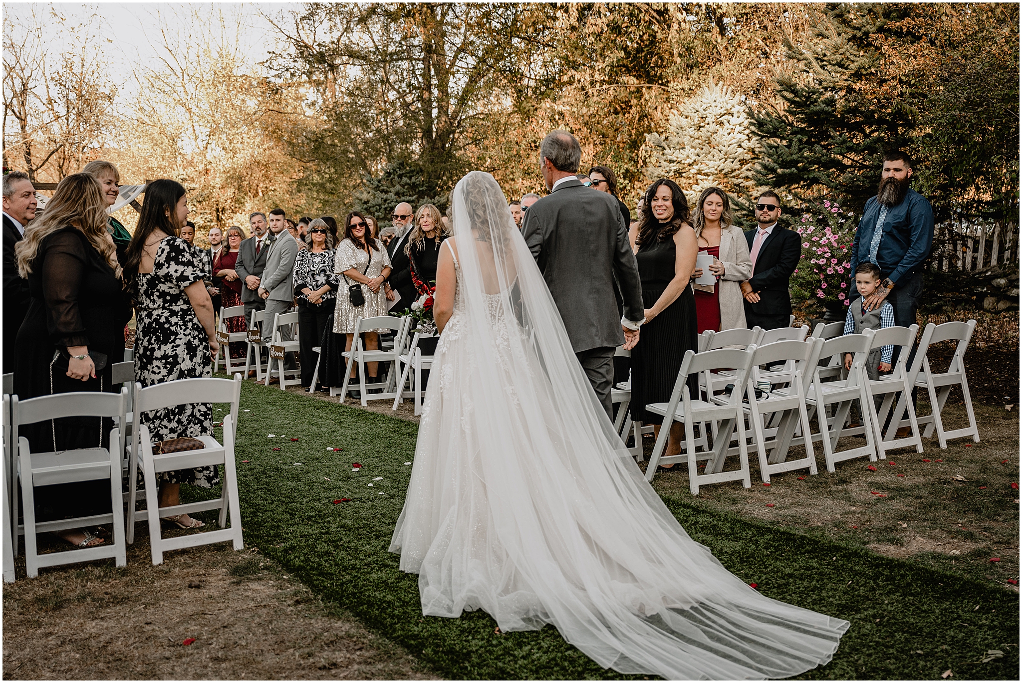 bride walks down aisle with veil trailing behind her on dad's arm at the Feast at Round Hill