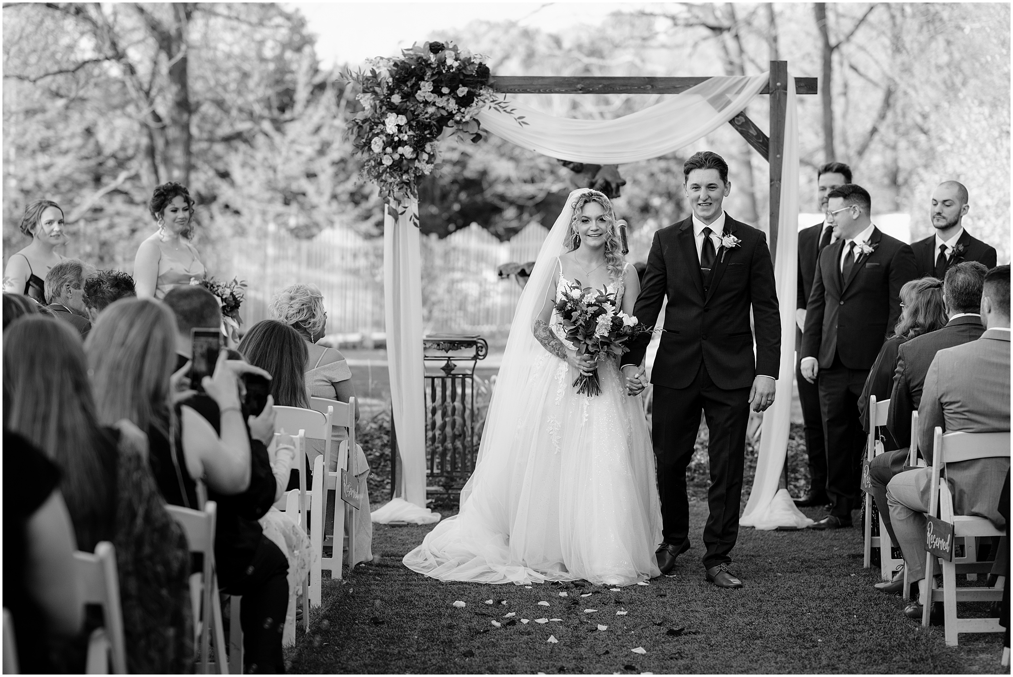 bride and groom smile turning to face guests after ceremony in front of wooden arbor at the Feast at Round Hill