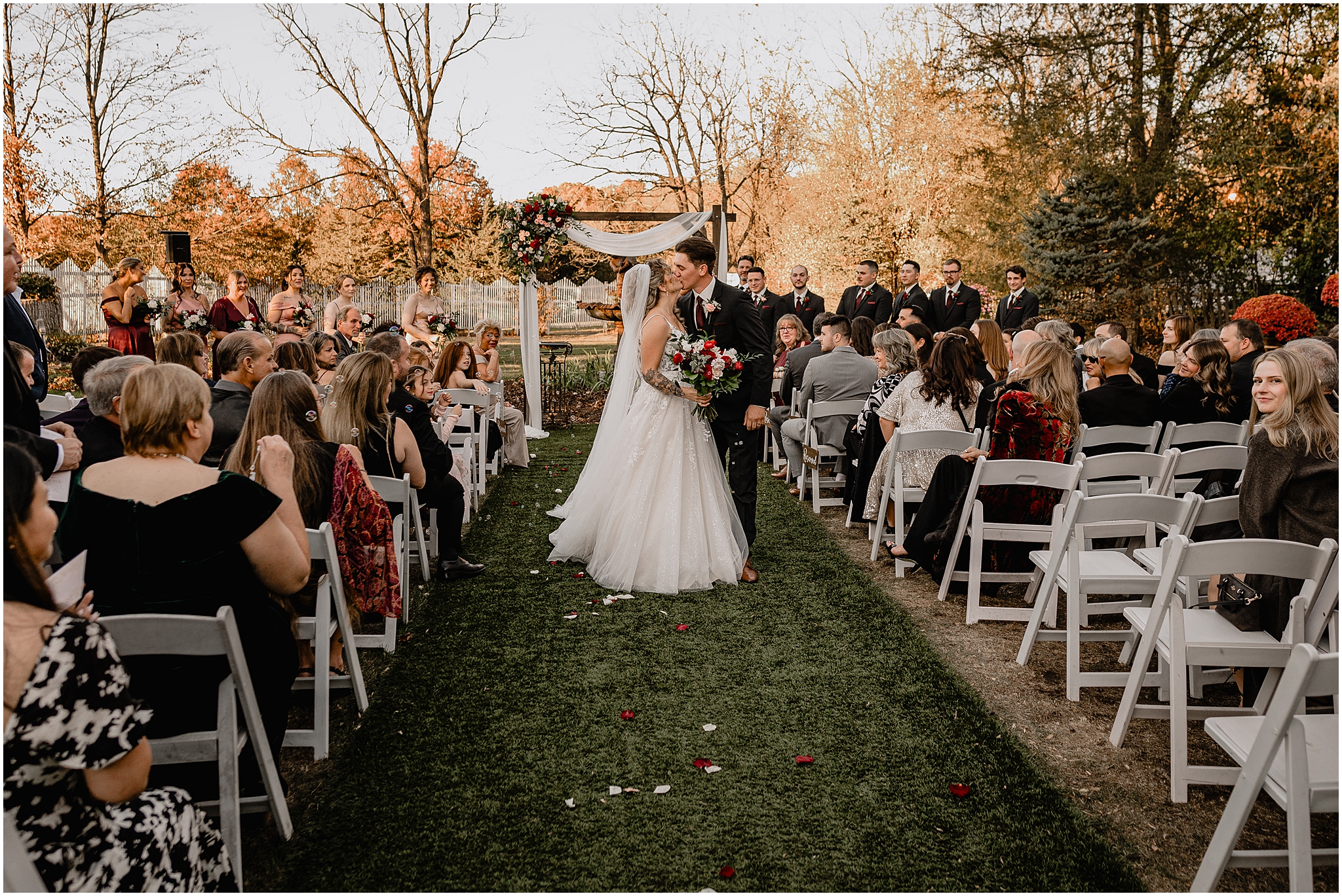 bride and groom kiss on aisle leaving garden wedding ceremony at the Feast at Round Hill