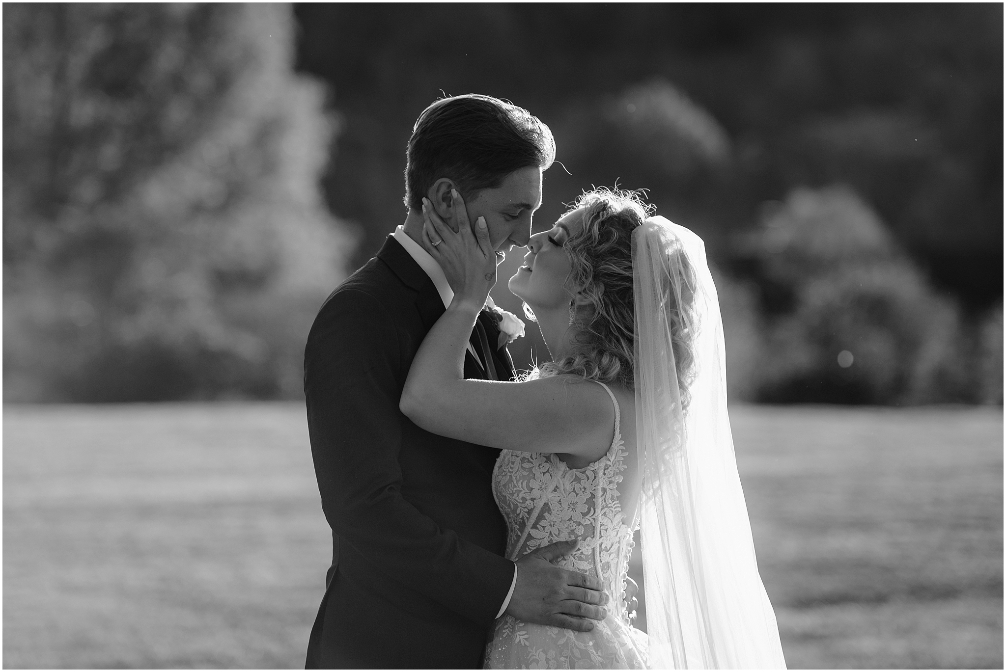 bride and groom lean to kiss each other with bride grasping groom's cheeks 