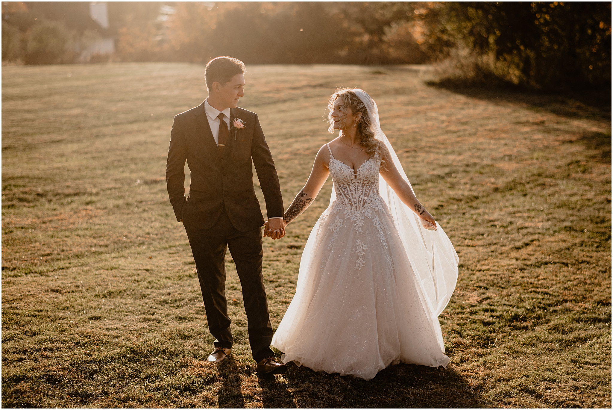 bride and groom hold hands walking across green lawn during fall wedding day in the Hudson Valley