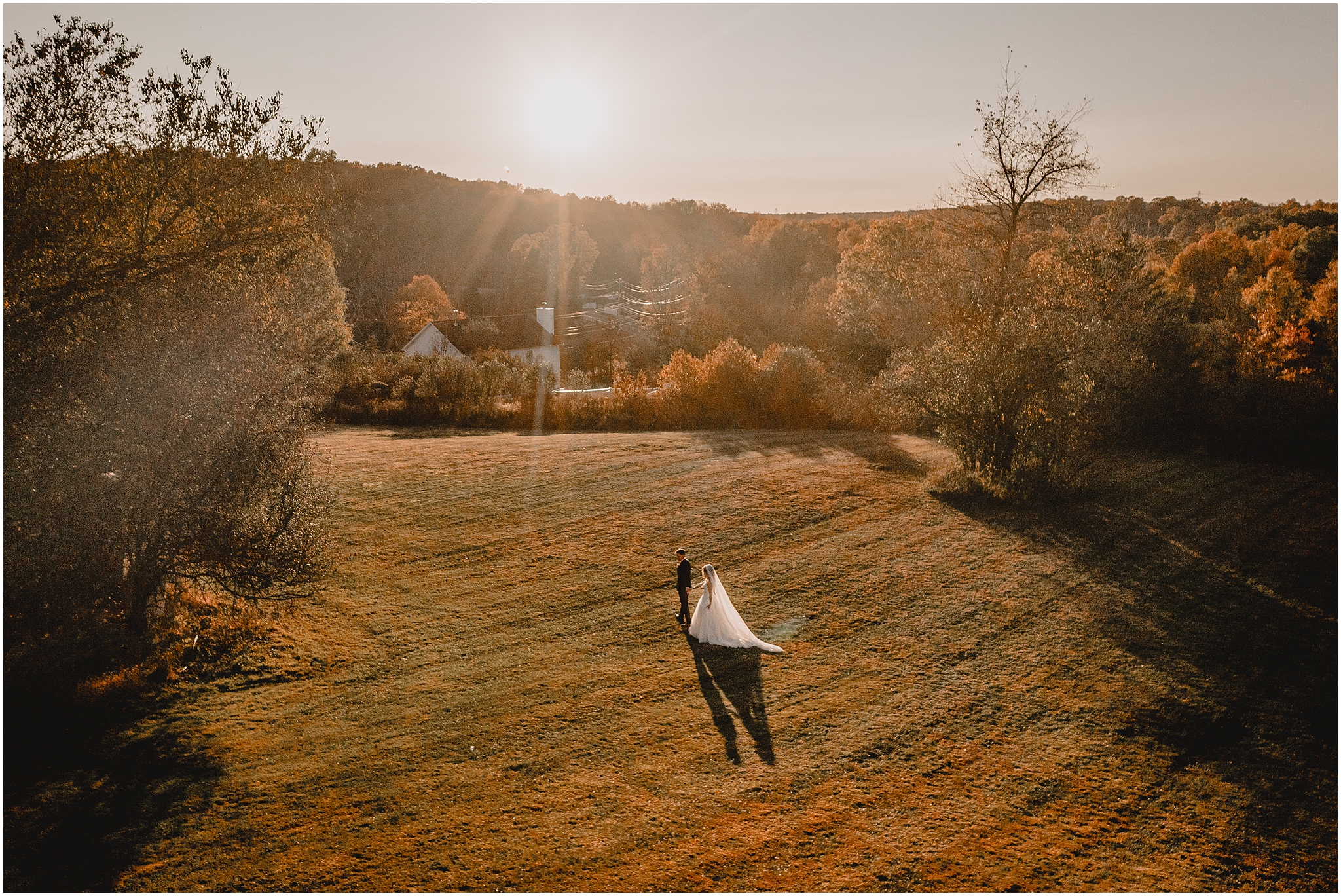 bride and groom hold hands walking across orange and green field in the Hudson Valley