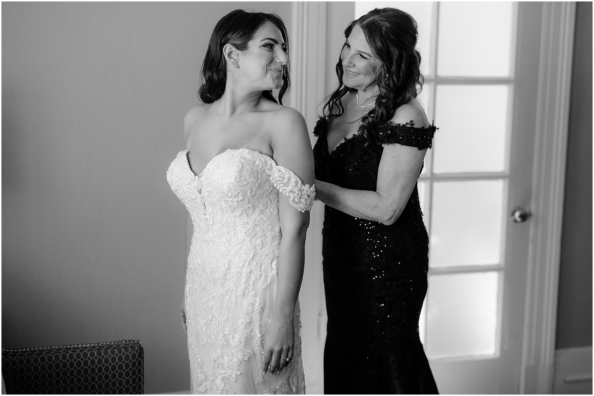 mother in black dress helps zip up bride into wedding gown during prep in New York 