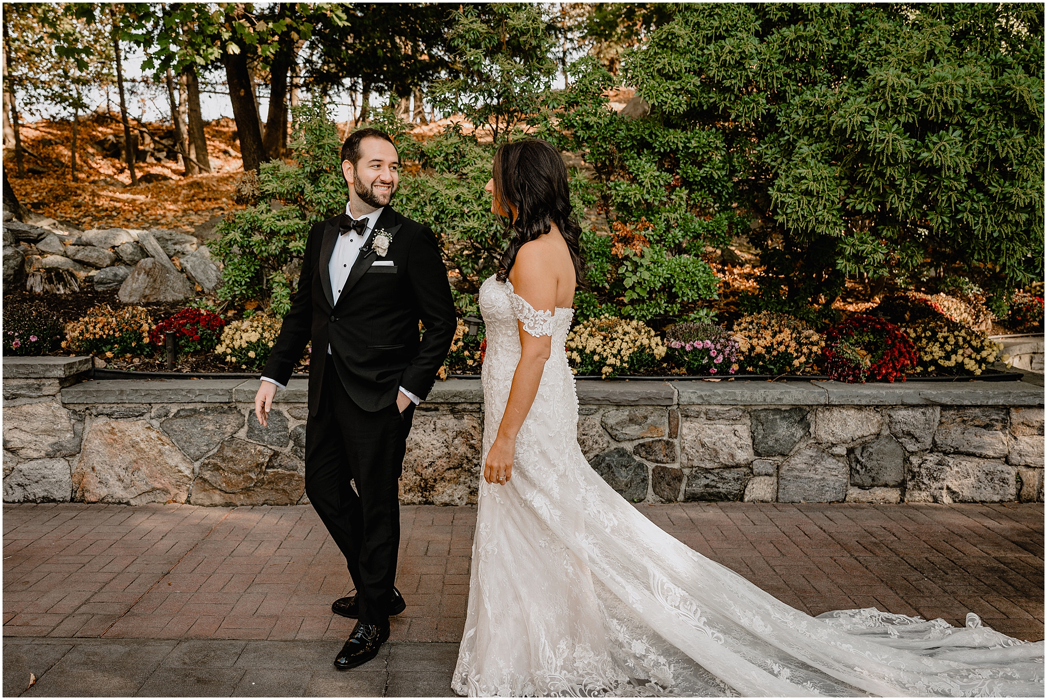 groom in black suit turns to look at bride during first look on the stone patio at Tappan Hill Mansion
