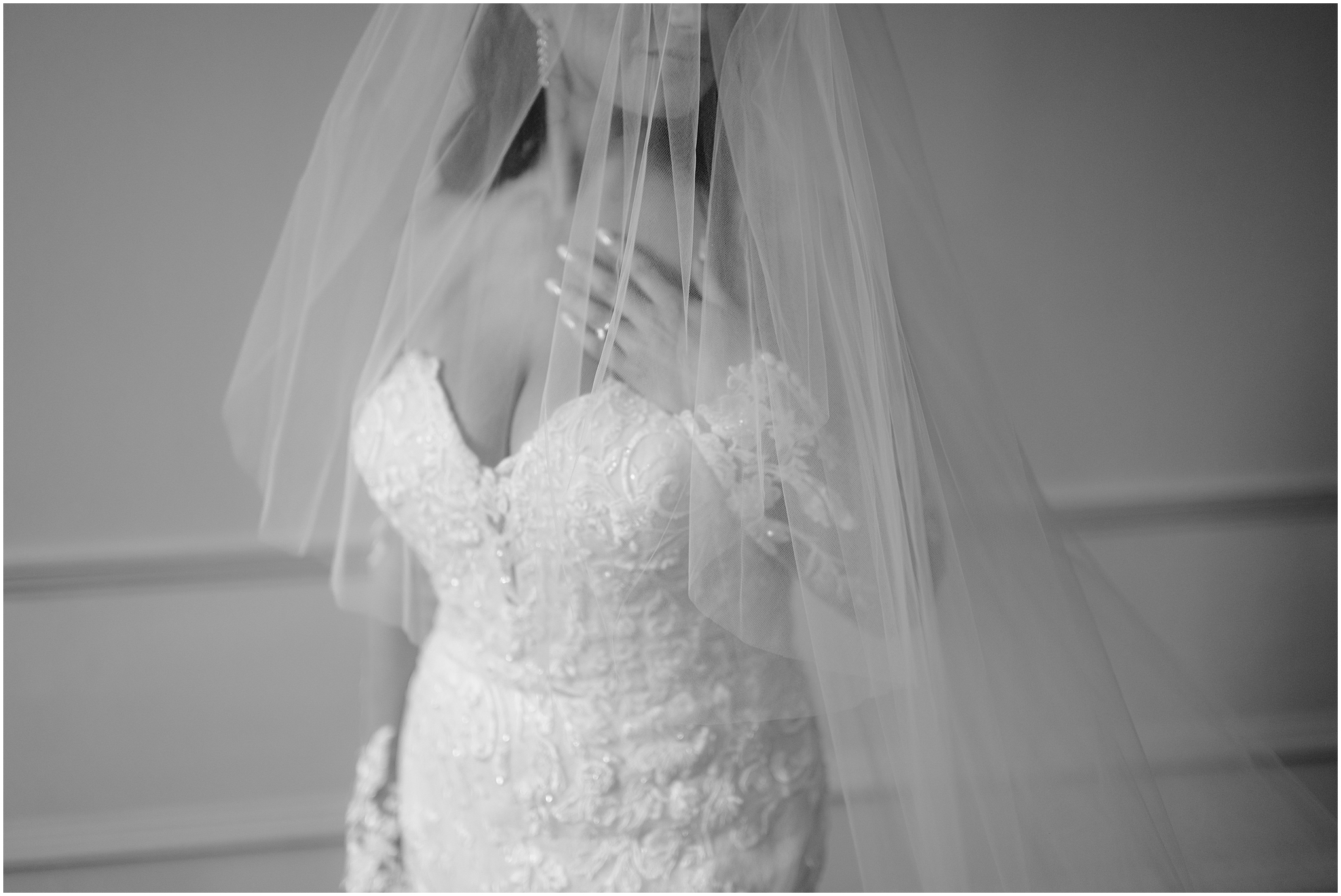 bride places left hand on her chest showing off ring and lace sleeve under veil