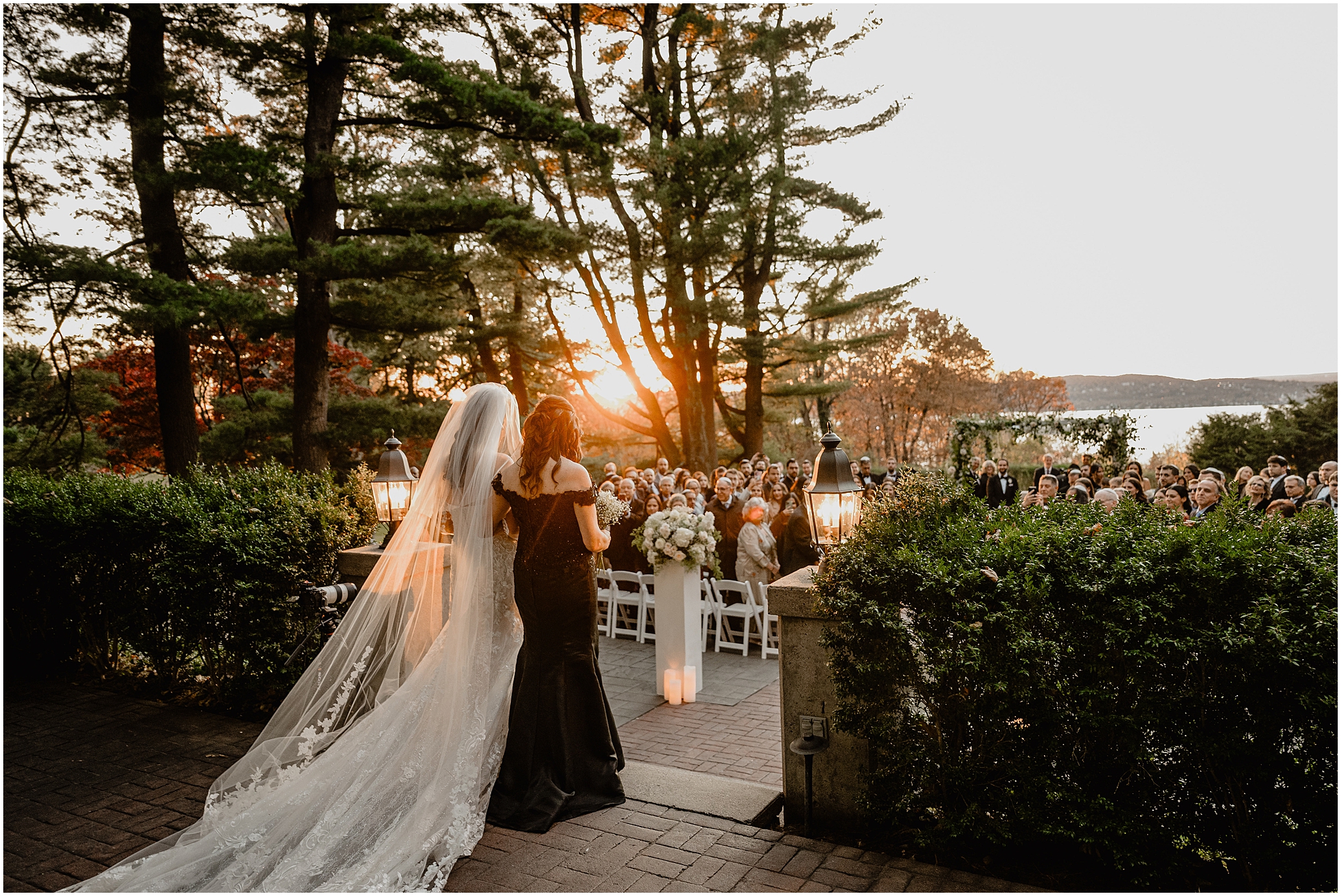 mother escorts bride to Jewish wedding ceremony on the patio at Tappan Hill Mansion at sunset
