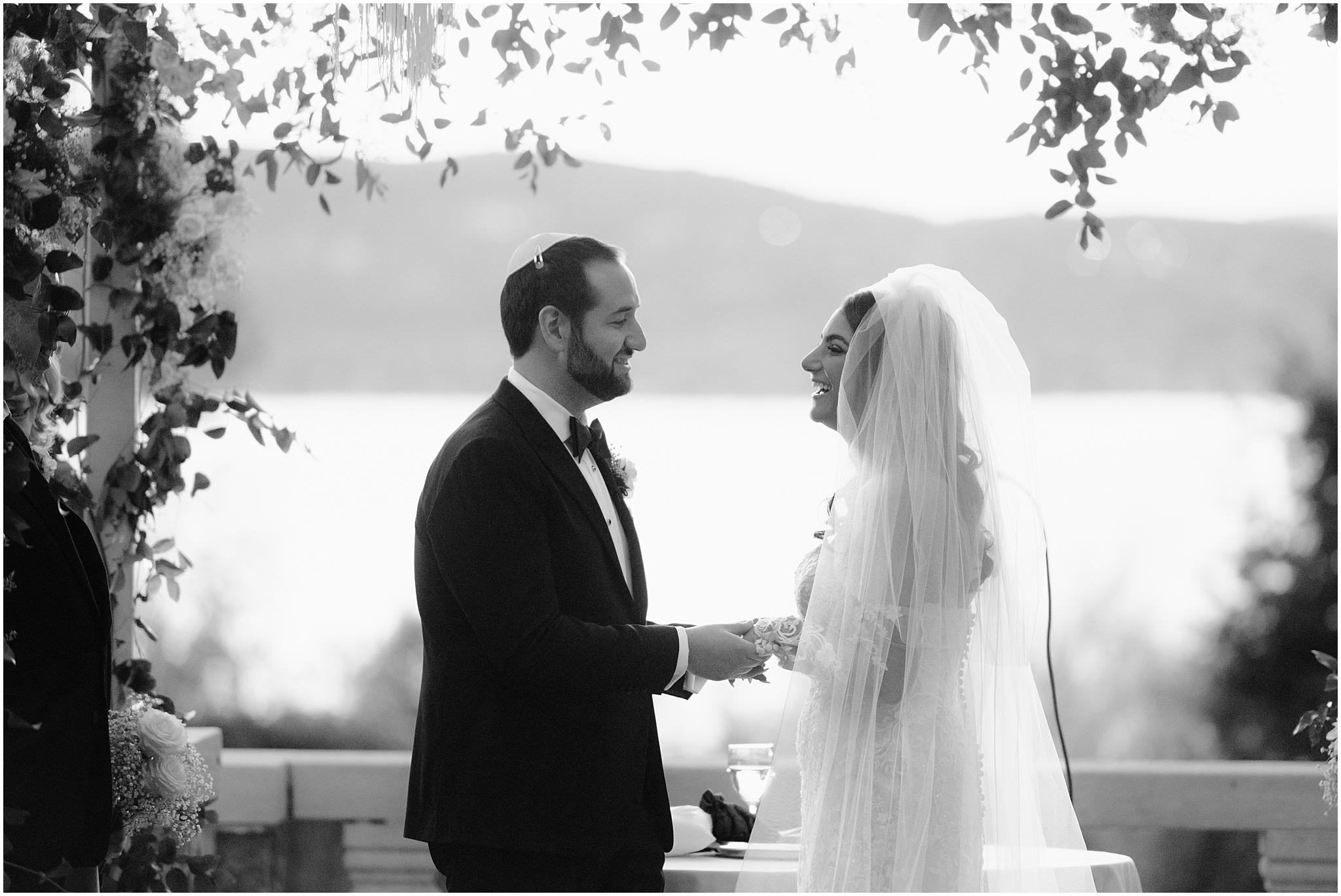 bride and groom hold hands under canopy during Jewish wedding ceremony on the patio at Tappan Hill Mansion