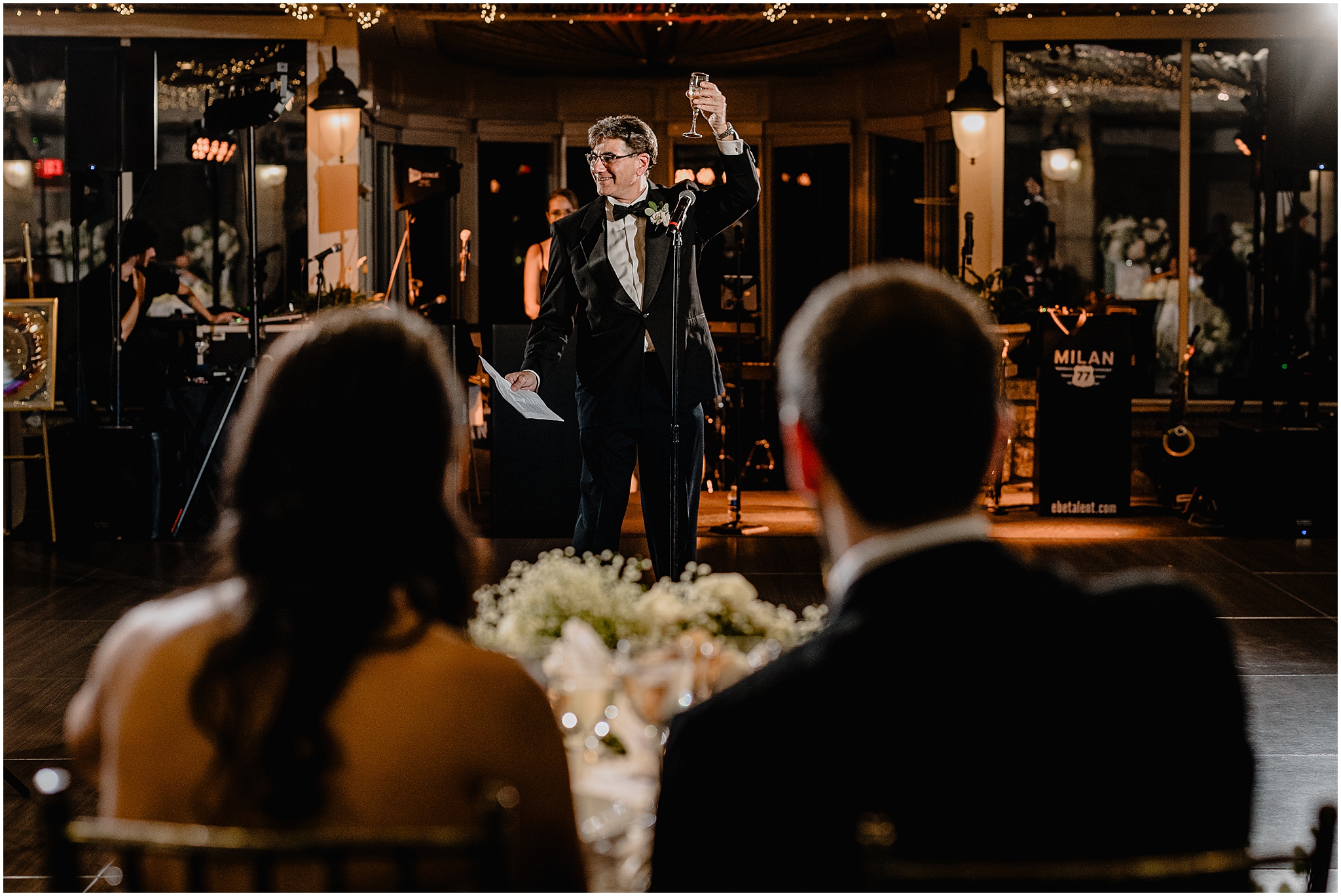 man lifts up drink during speech at Tarrytown NY wedding reception for bride and groom