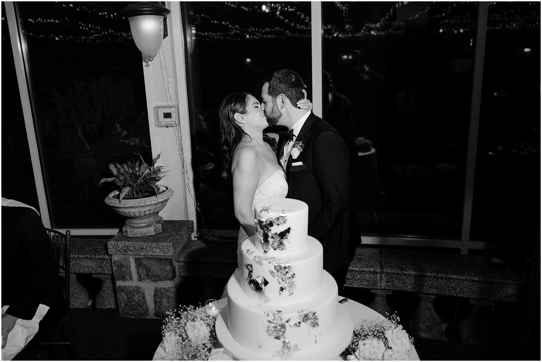 bride and groom kiss behind tiered wedding cake in the window at Tappan Hill Mansion