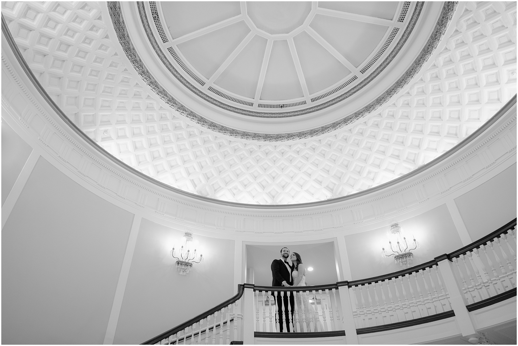 newlyweds hug at the top of staircase under dome in Tappan Hill Mansion