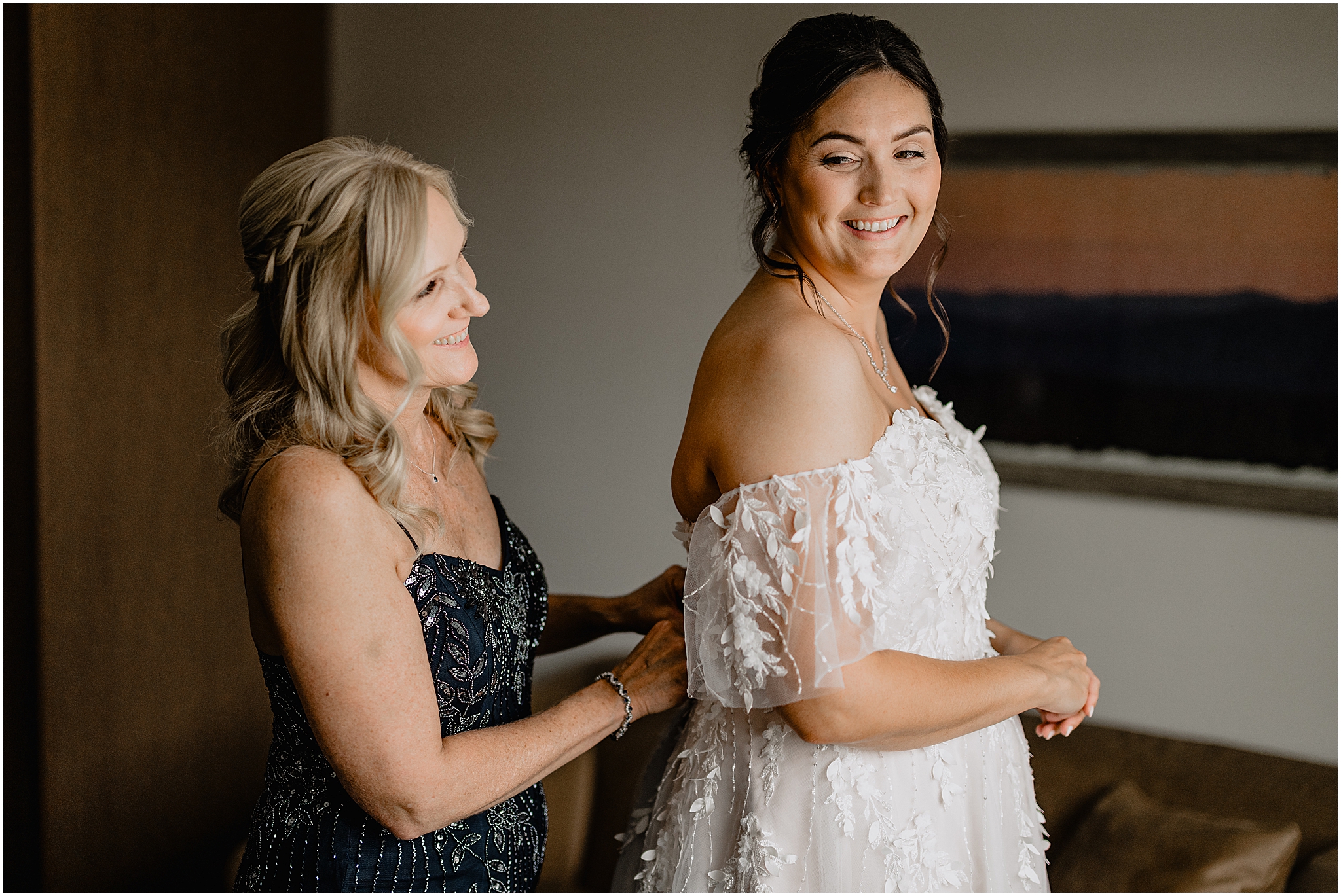 mother helps bride into wedding gown during prep at New Jersey hotel