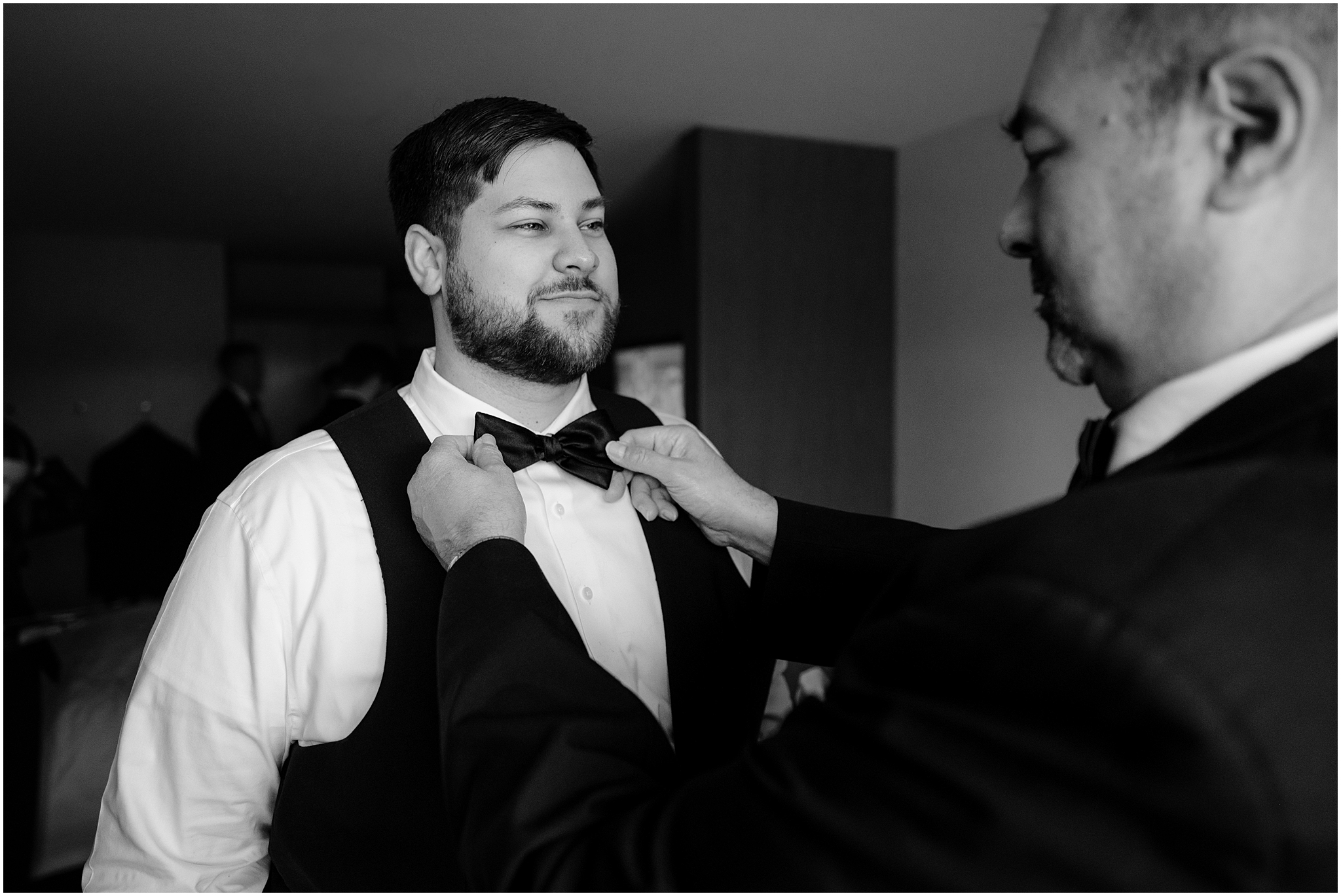 father adjusts black bow tie for groom on wedding day