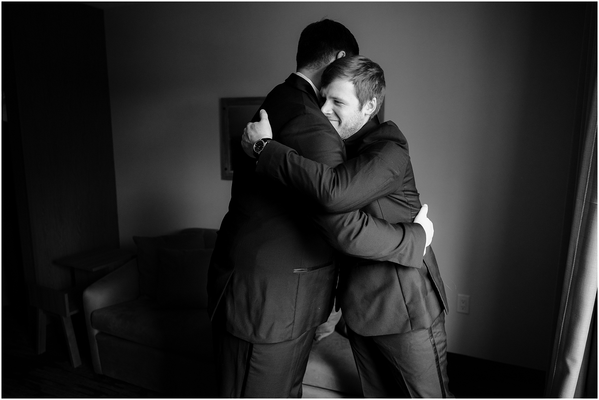 groom and groomsman hug during wedding prep in hotel in New Jersey