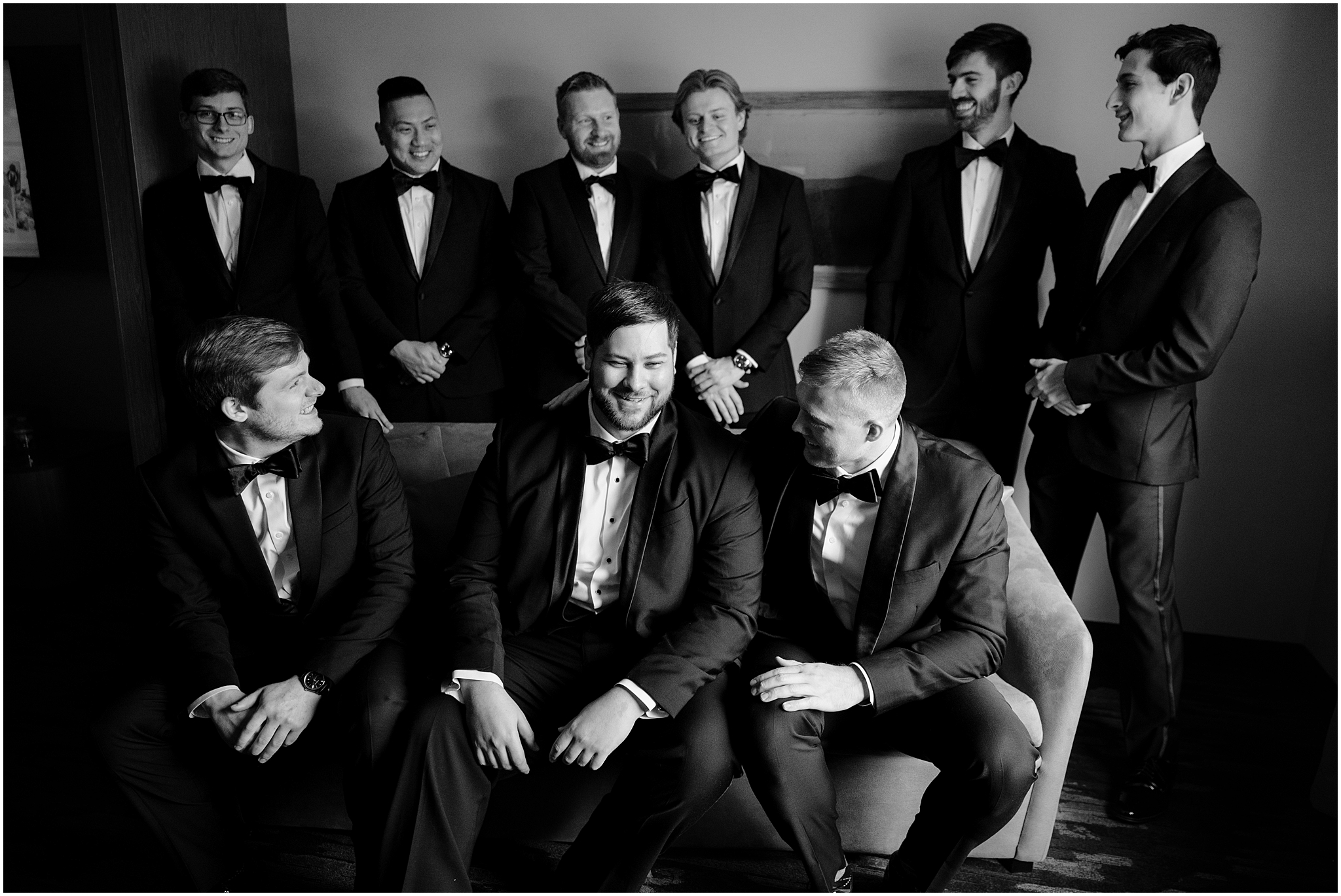 groom sits on couch with groomsmen around him in suite at the Perona Farms Reserve