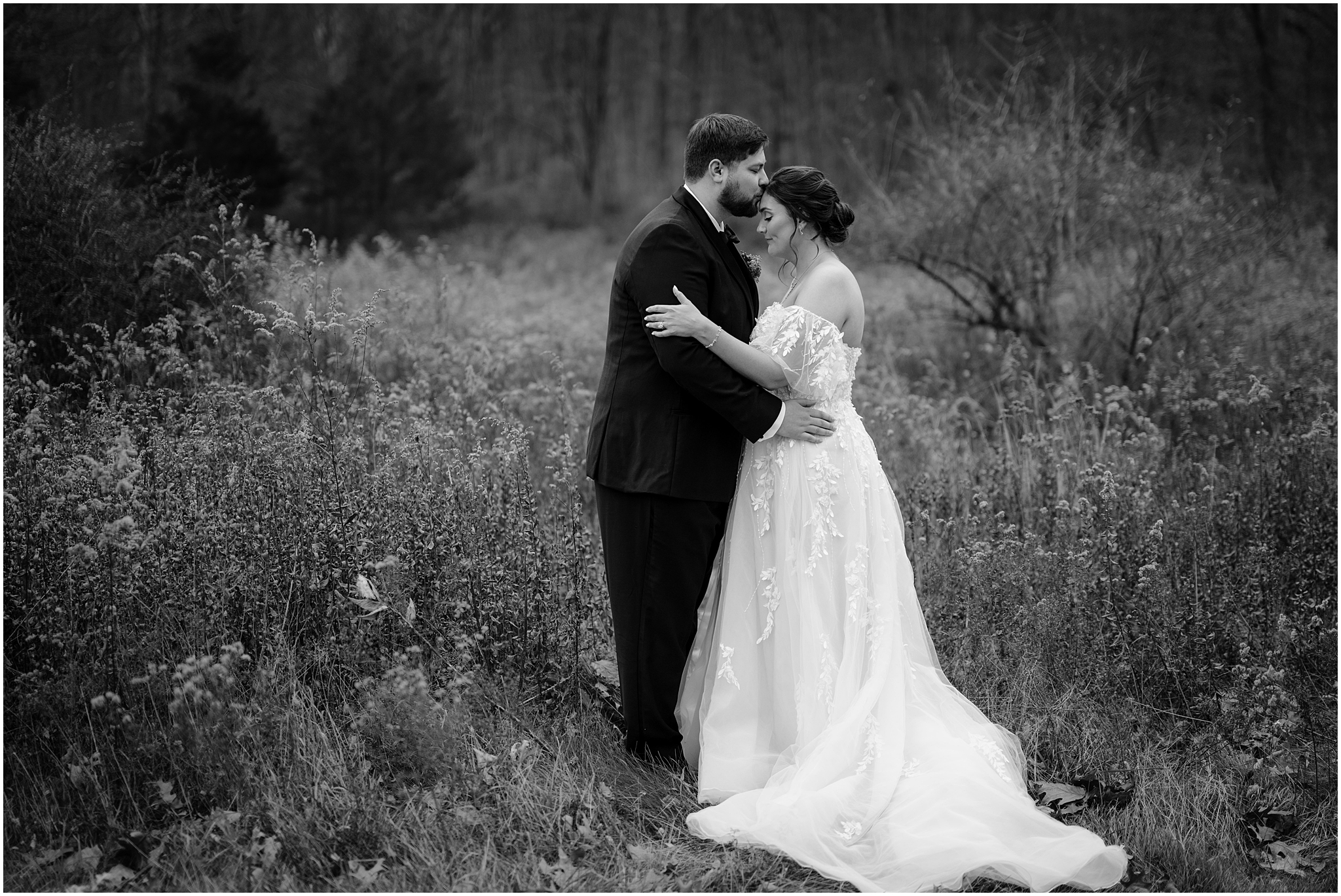 groom hugs bride kissing her forehead during wedding portraits in field at the Perona Farms Reserve