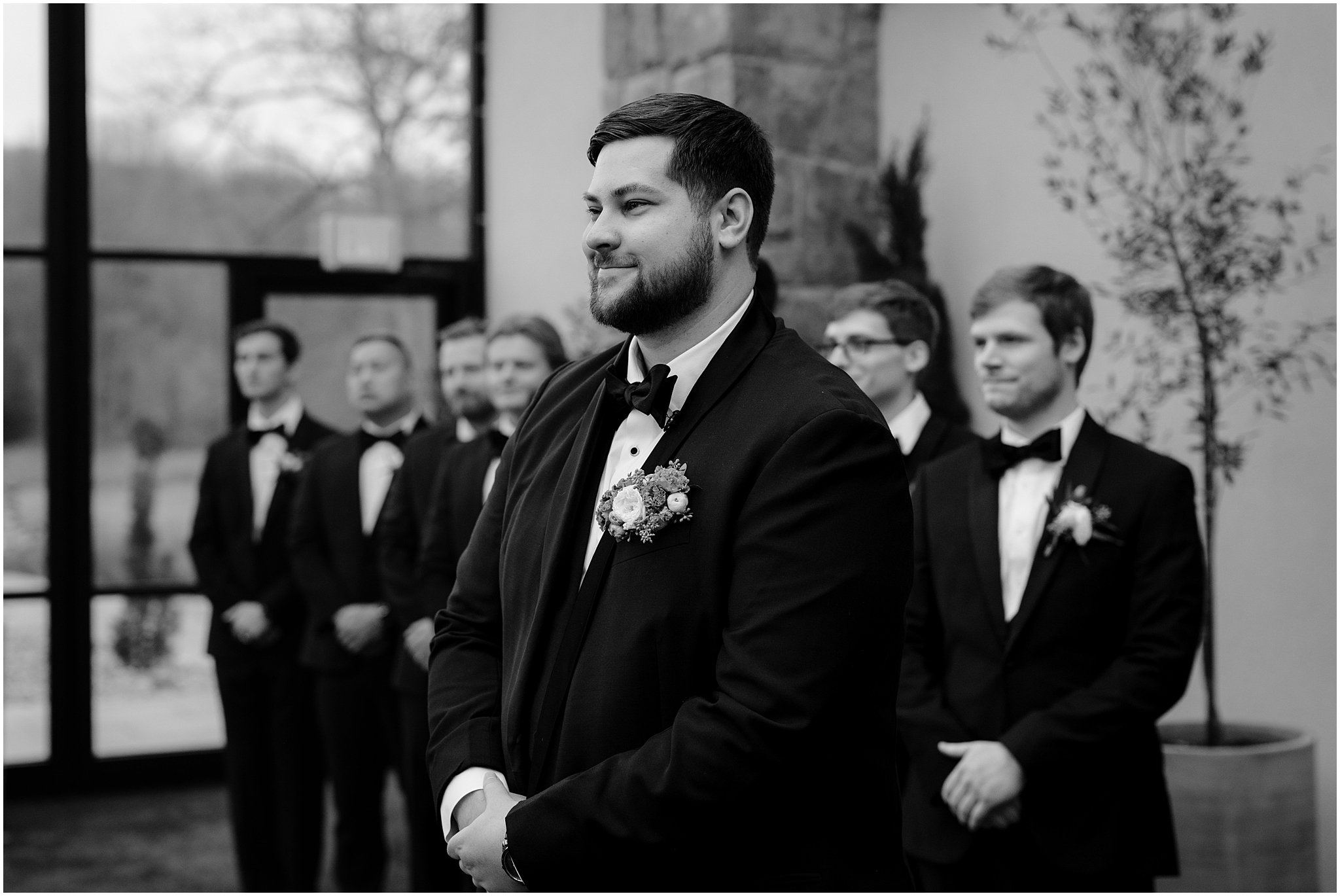 groom smiles watching aisle during wedding ceremony in the atrium at Perona Farms Reserve