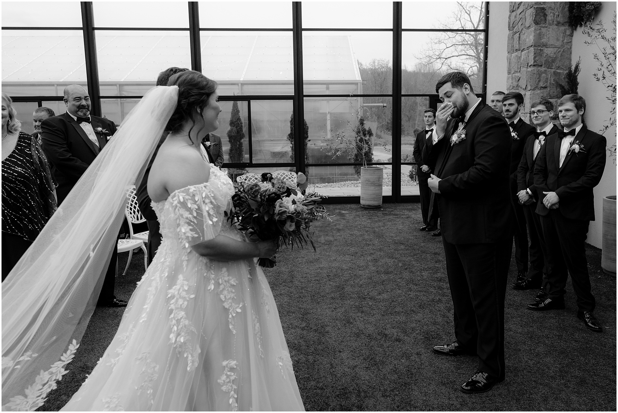groom wipes away tears during wedding ceremony in the atrium at Perona Farms Reserve