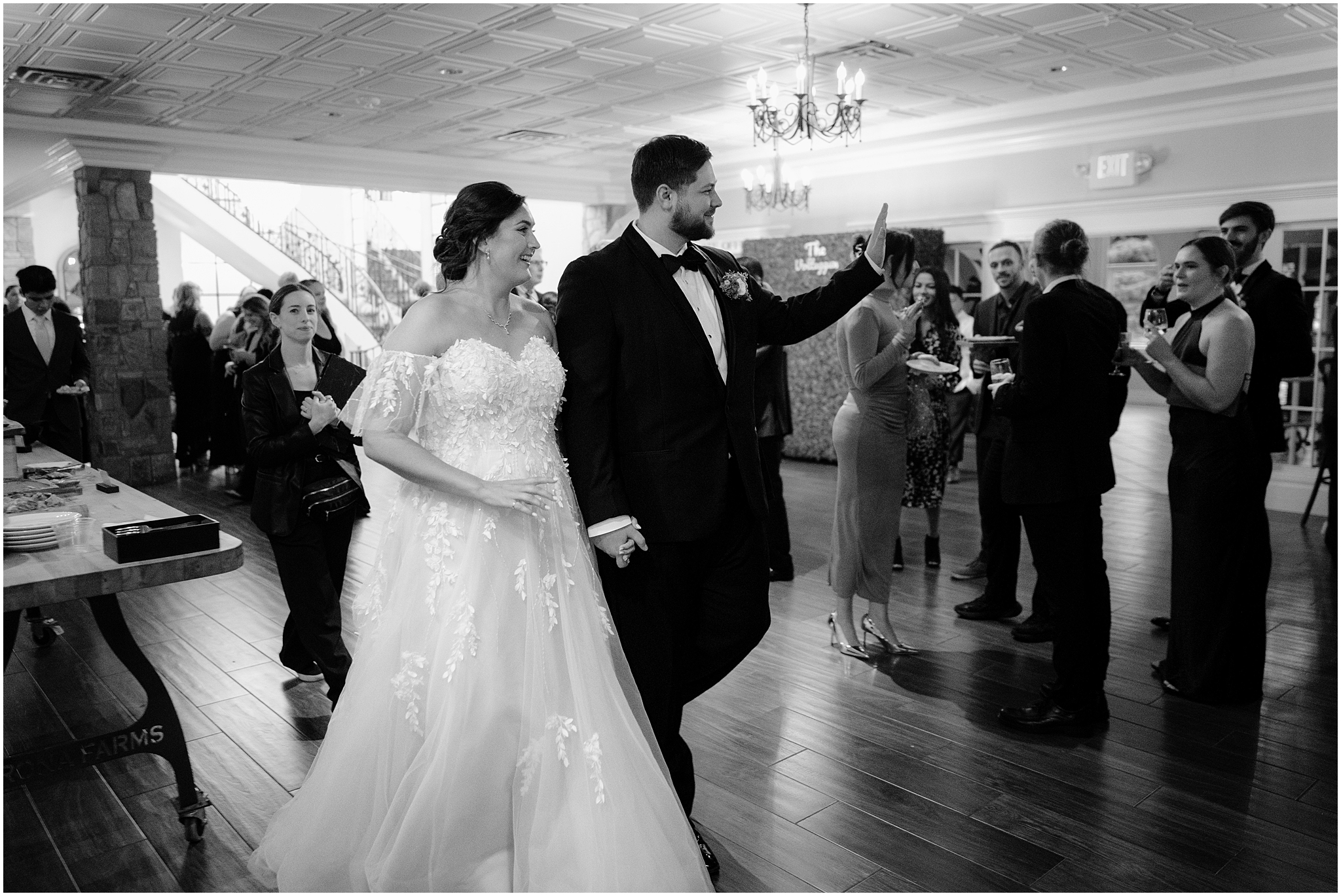 bride and groom smile waving at guests walking through wedding reception in Andover NJ