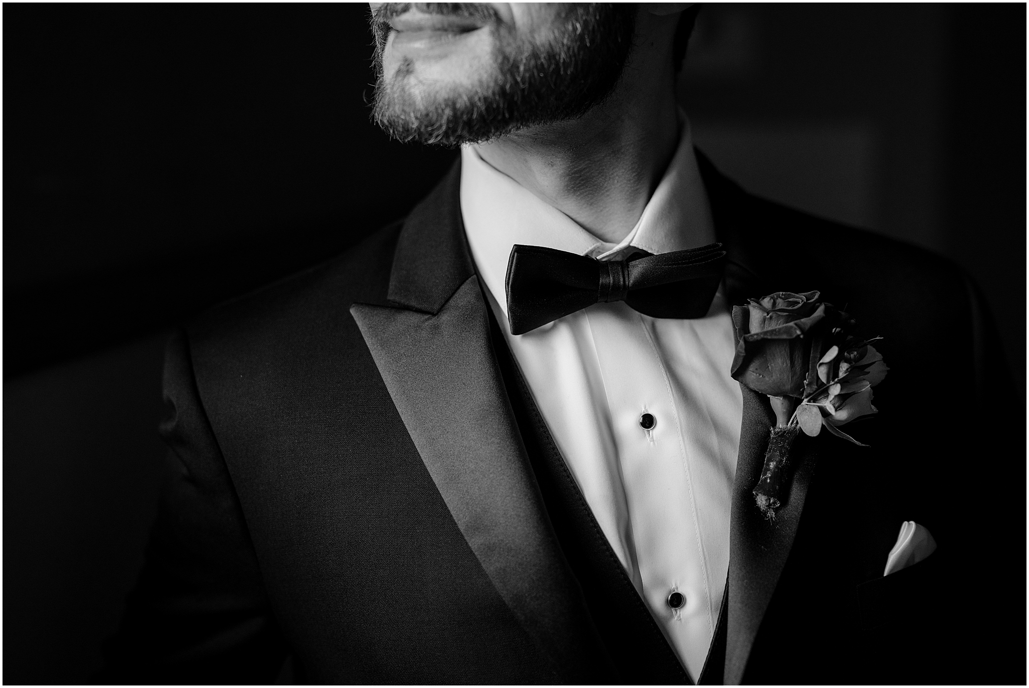 closeup of black bow tie for groom above rose on lapel