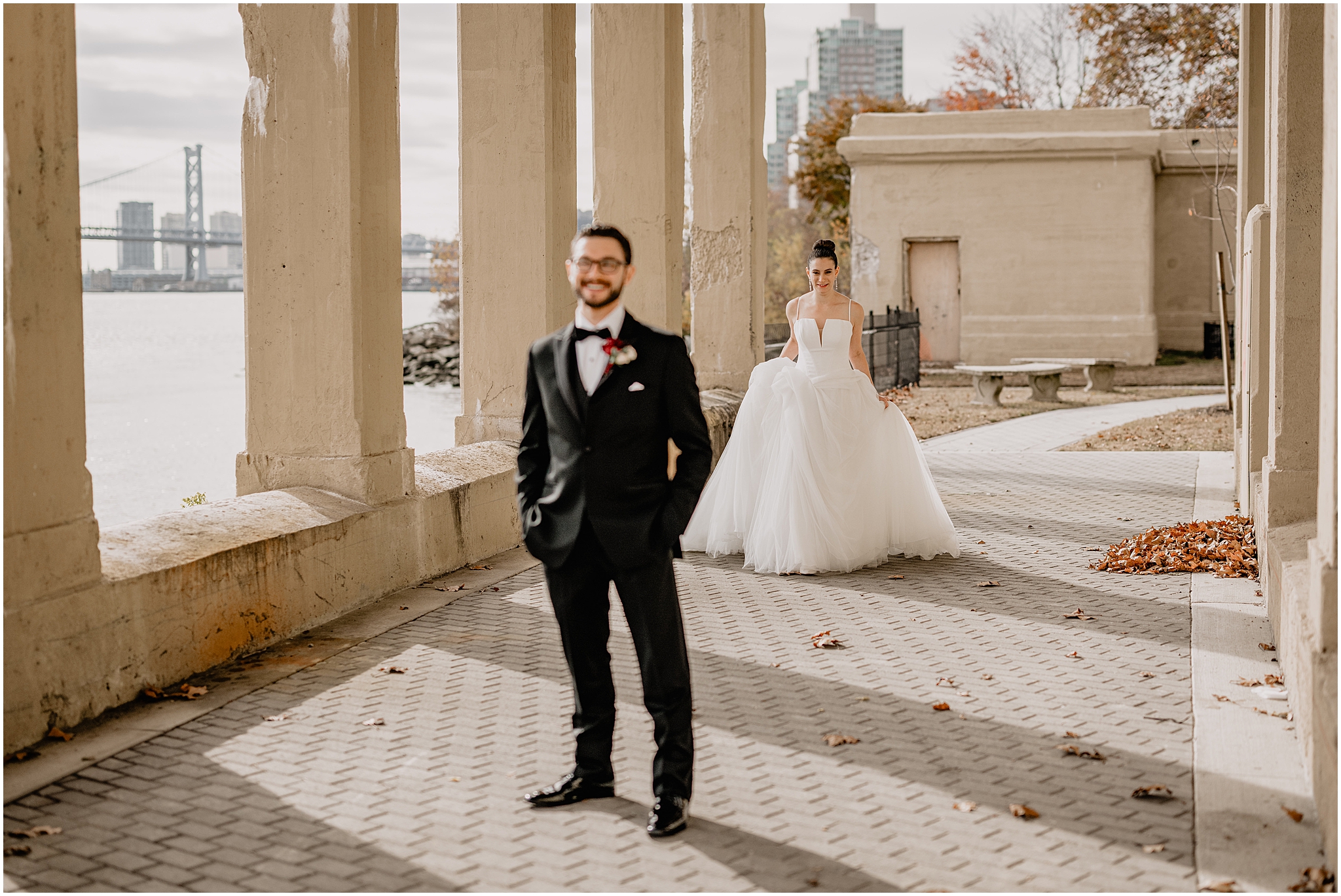 bride walks to meet groom for first look under bridge at Penn Landing along the Delaware River