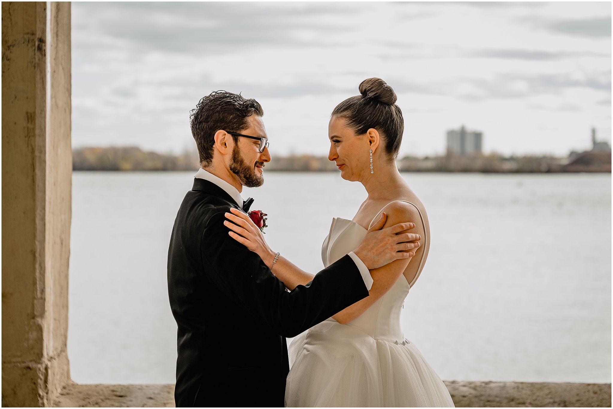 bride and groom hug crying in front of Penn Landing along the Delaware River